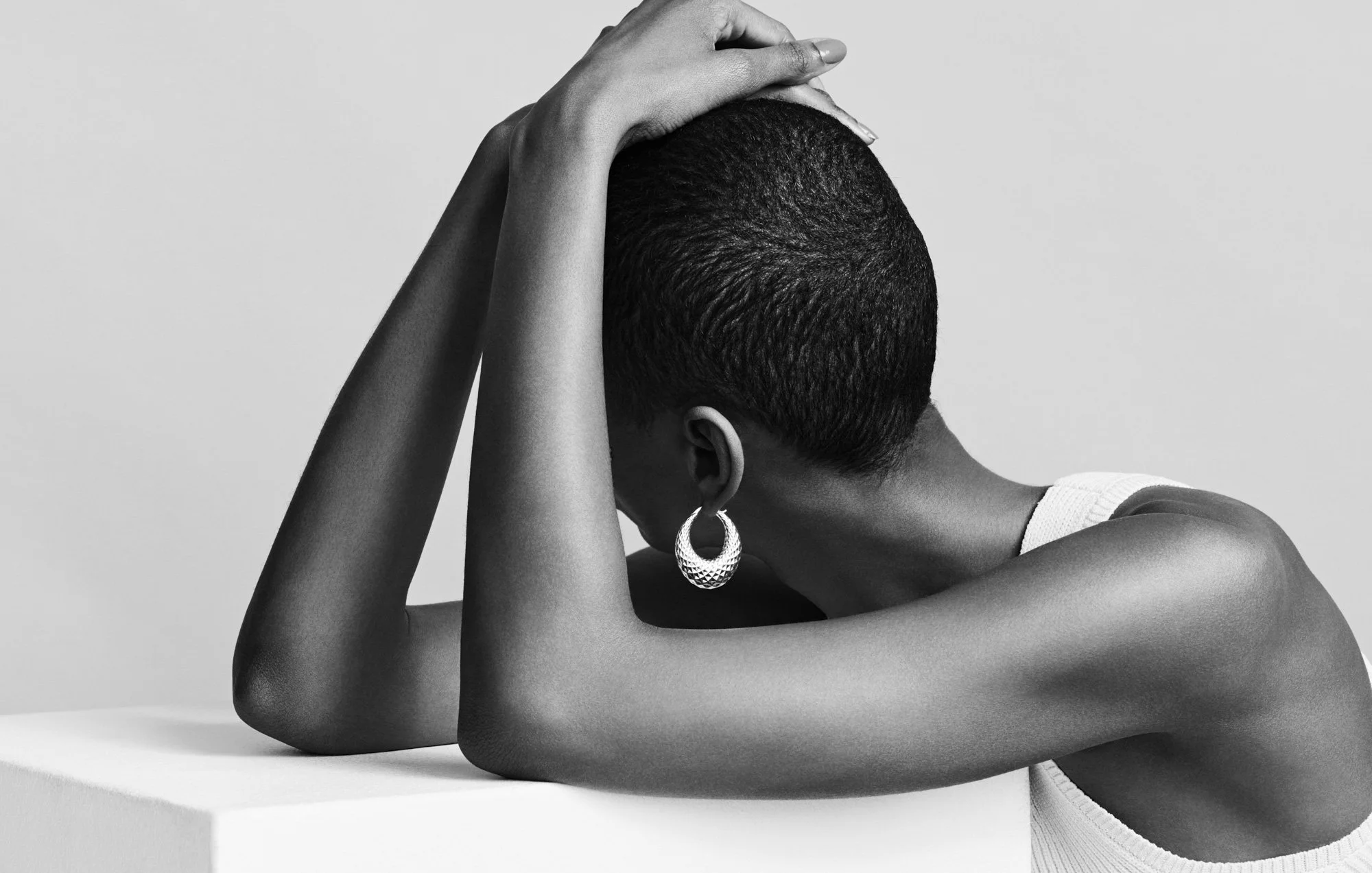 Hoop earring in black and white, arms over the head, jewellery photographer London Benjamin Kaufmann