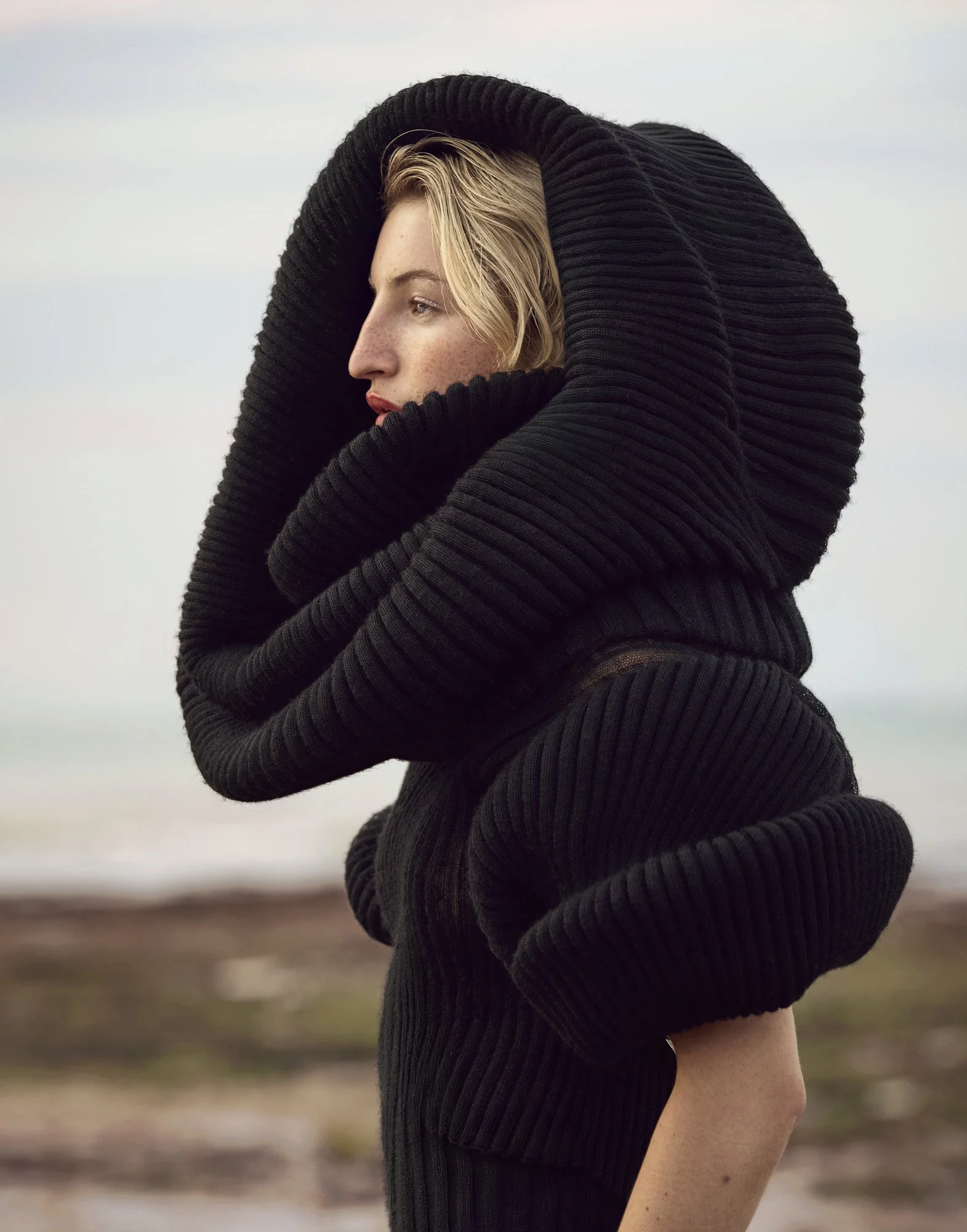 Sculptural black knit hood on the coast, fashion and beauty photography by Benjamin Kaufmann