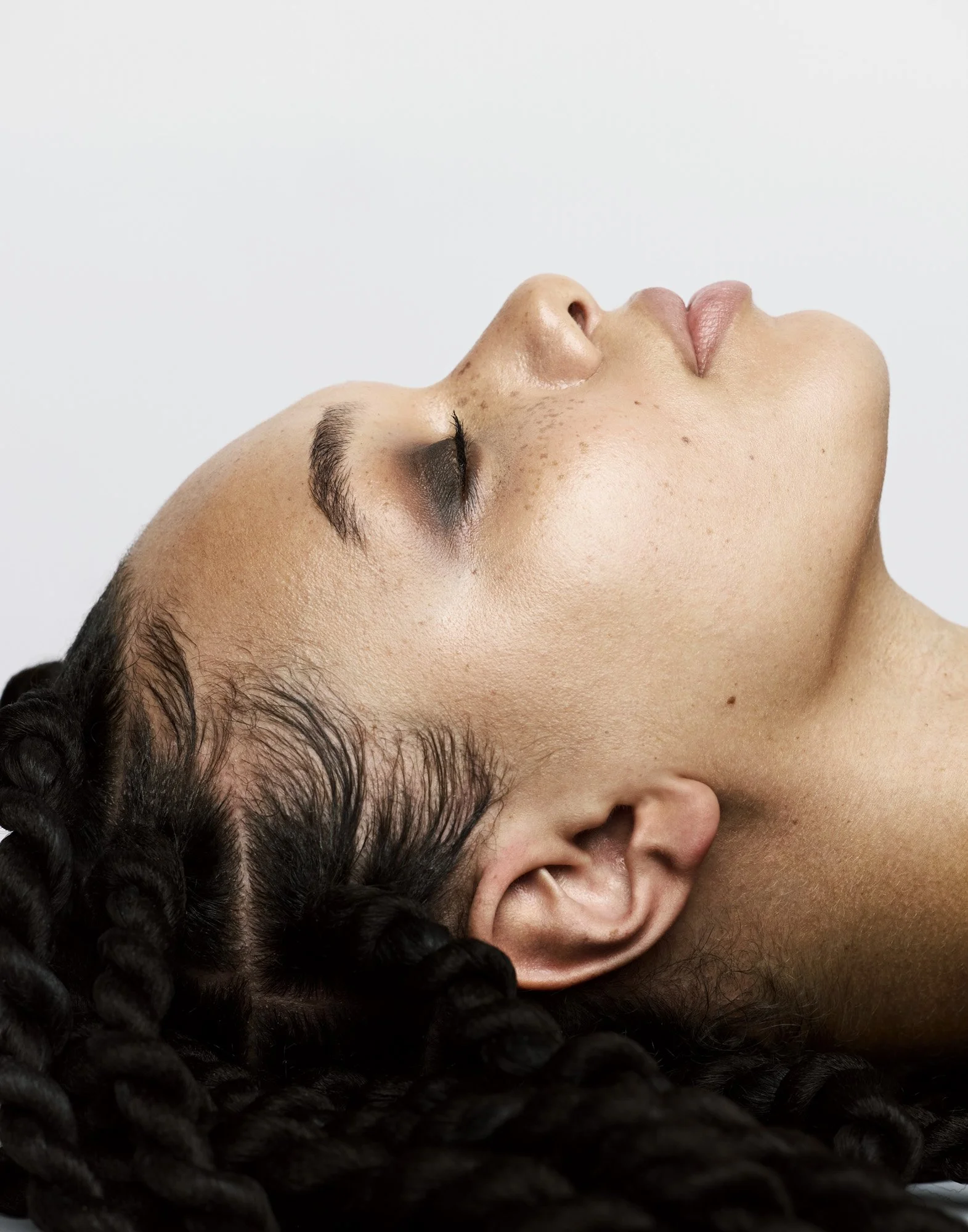 Braided hair and dewy skin, head tilted back, beauty photographer London Benjamin Kaufmann