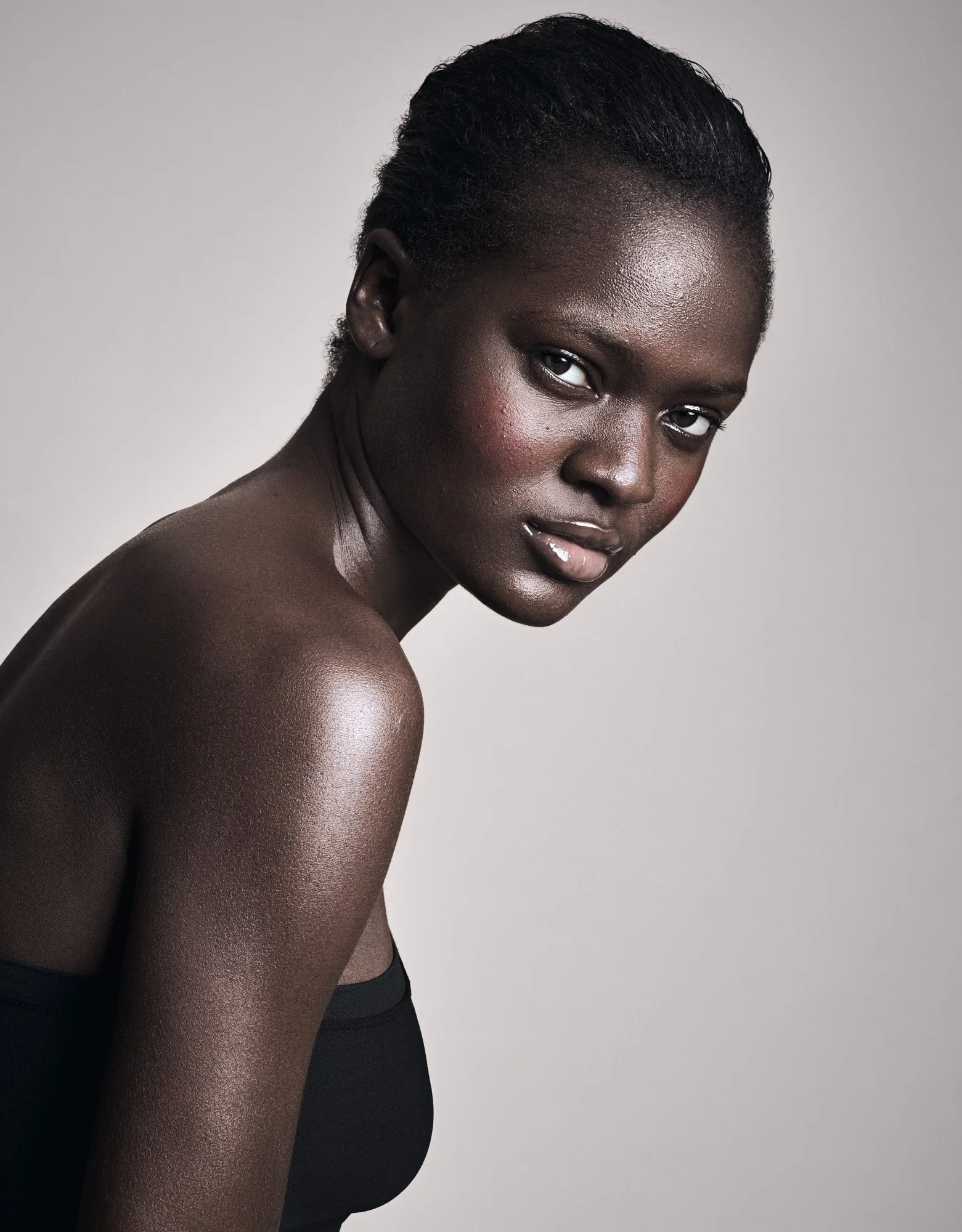 Glowing bare shoulder on dark skin, skin and make-up photography London by Benjamin Kaufmann