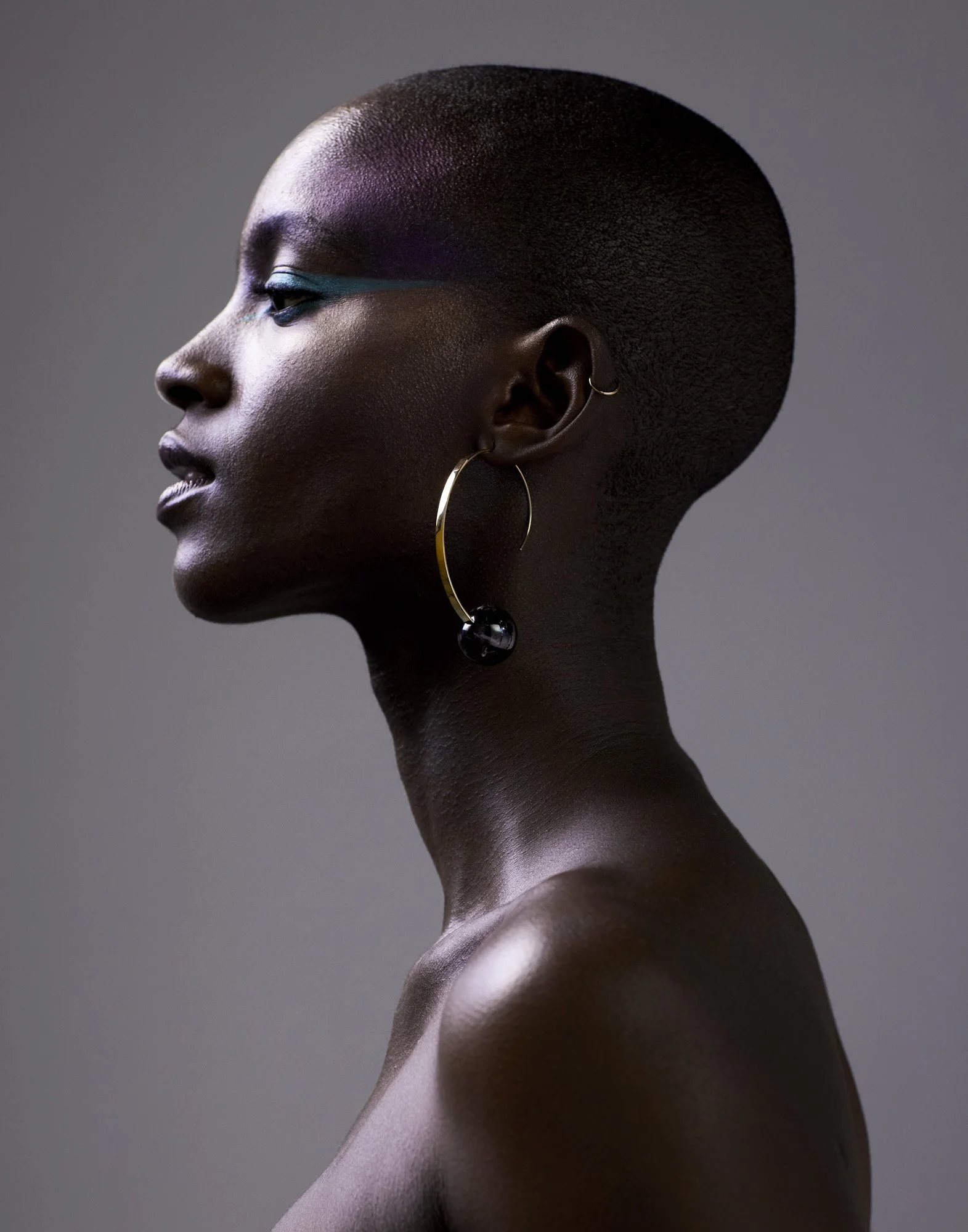 Violet eyeshadow and teal liner in profile on dark skin, beauty photographer London Benjamin Kaufmann