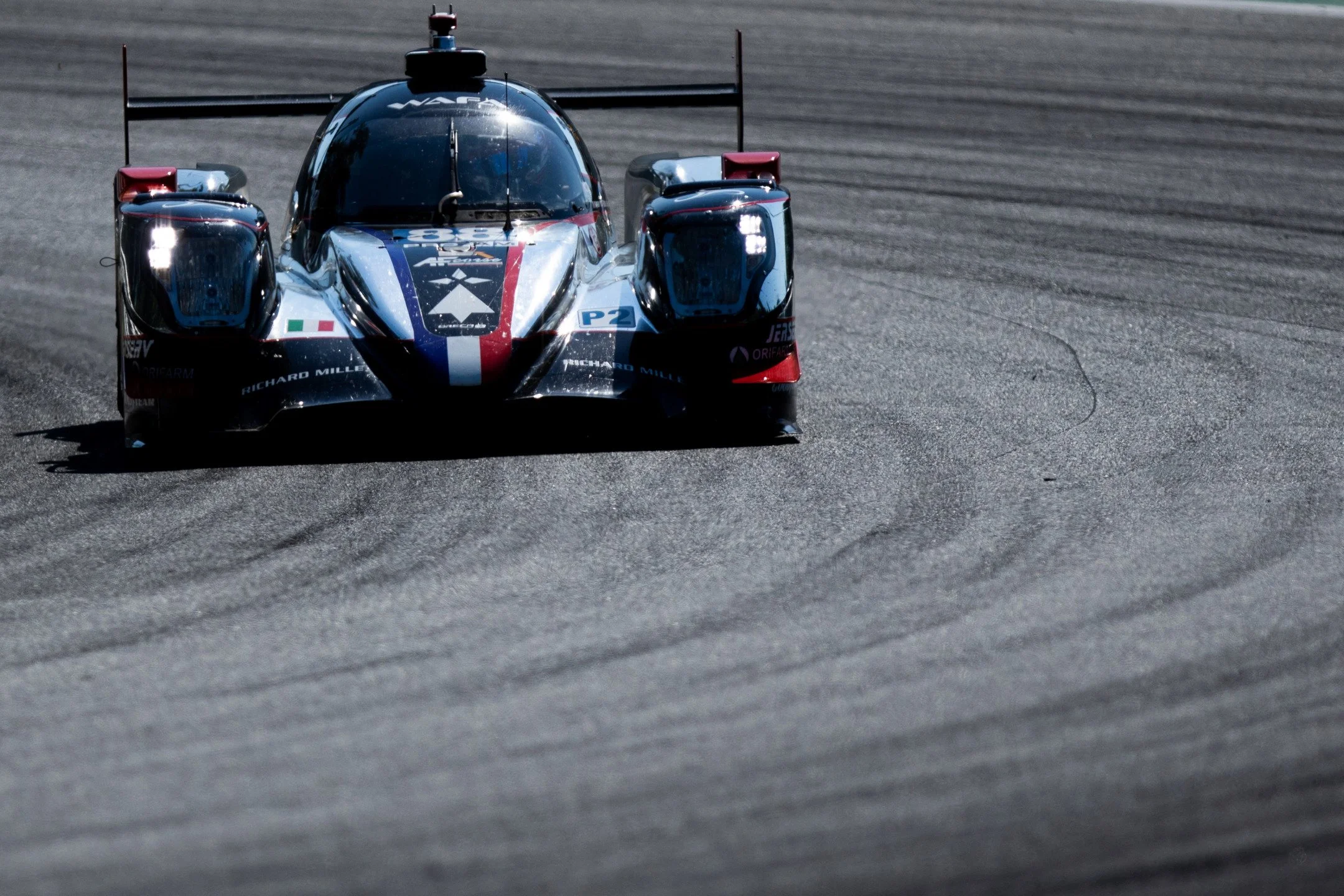 Auto da corsa sportiva su pista con colori blu, rosso e bianco, vista frontale