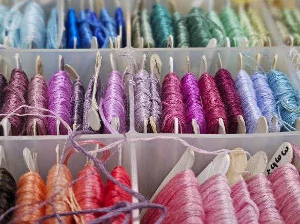A box of embroidery thread arranged by color gradient
