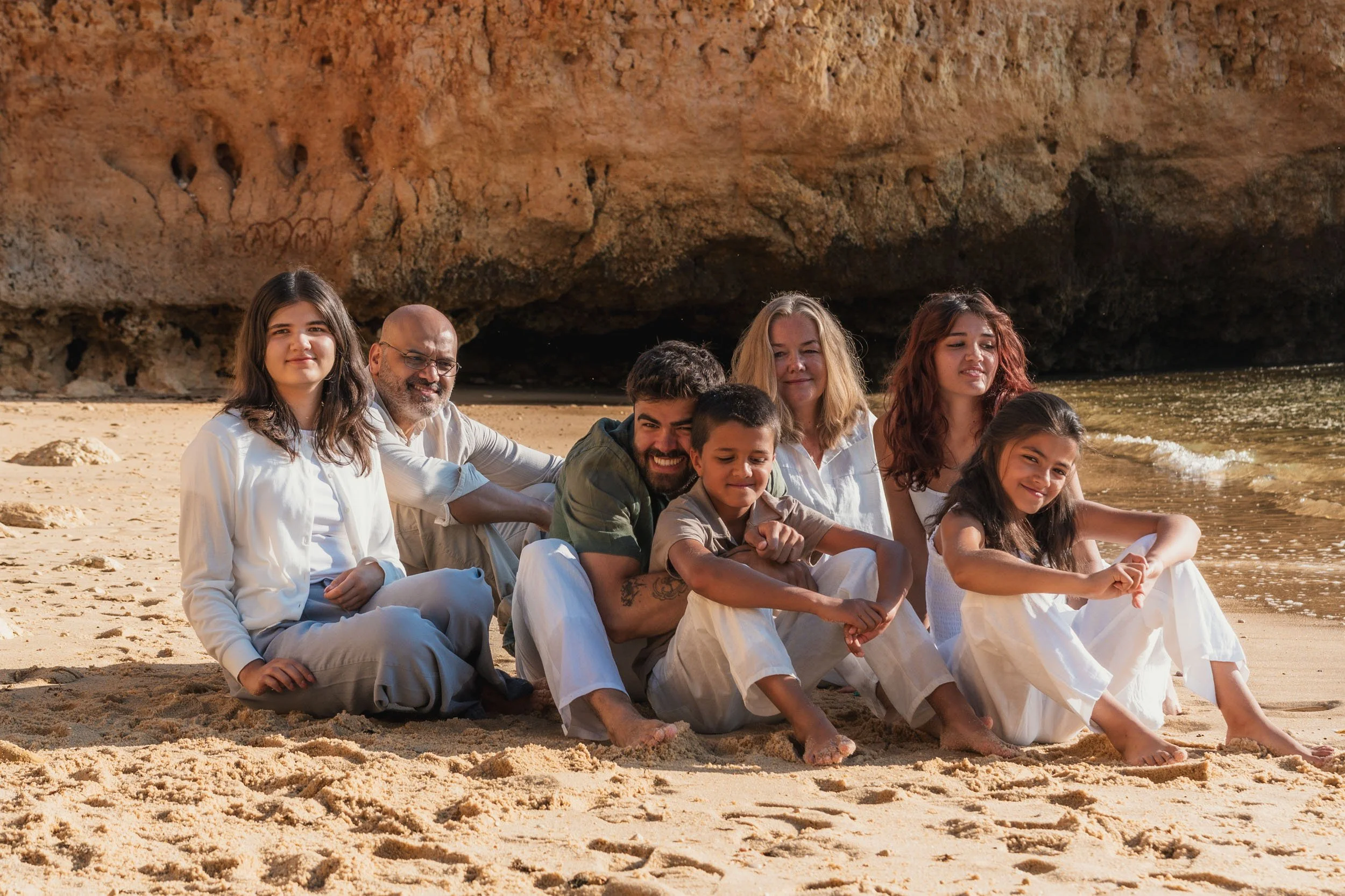 Family sitting on the sand at Praia do Camilo during a golden hour photoshoot in Lagos Algarve.