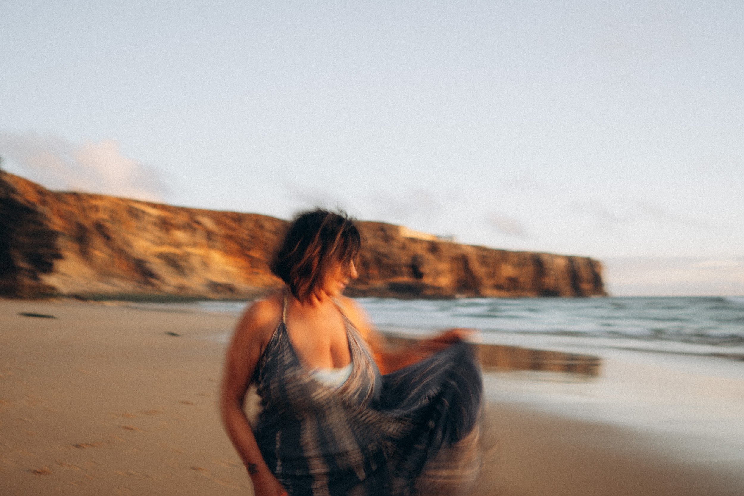 Portrait of a woman dancing during a couple photoshoot in Sagres, surrounded by cliffs and ocean.