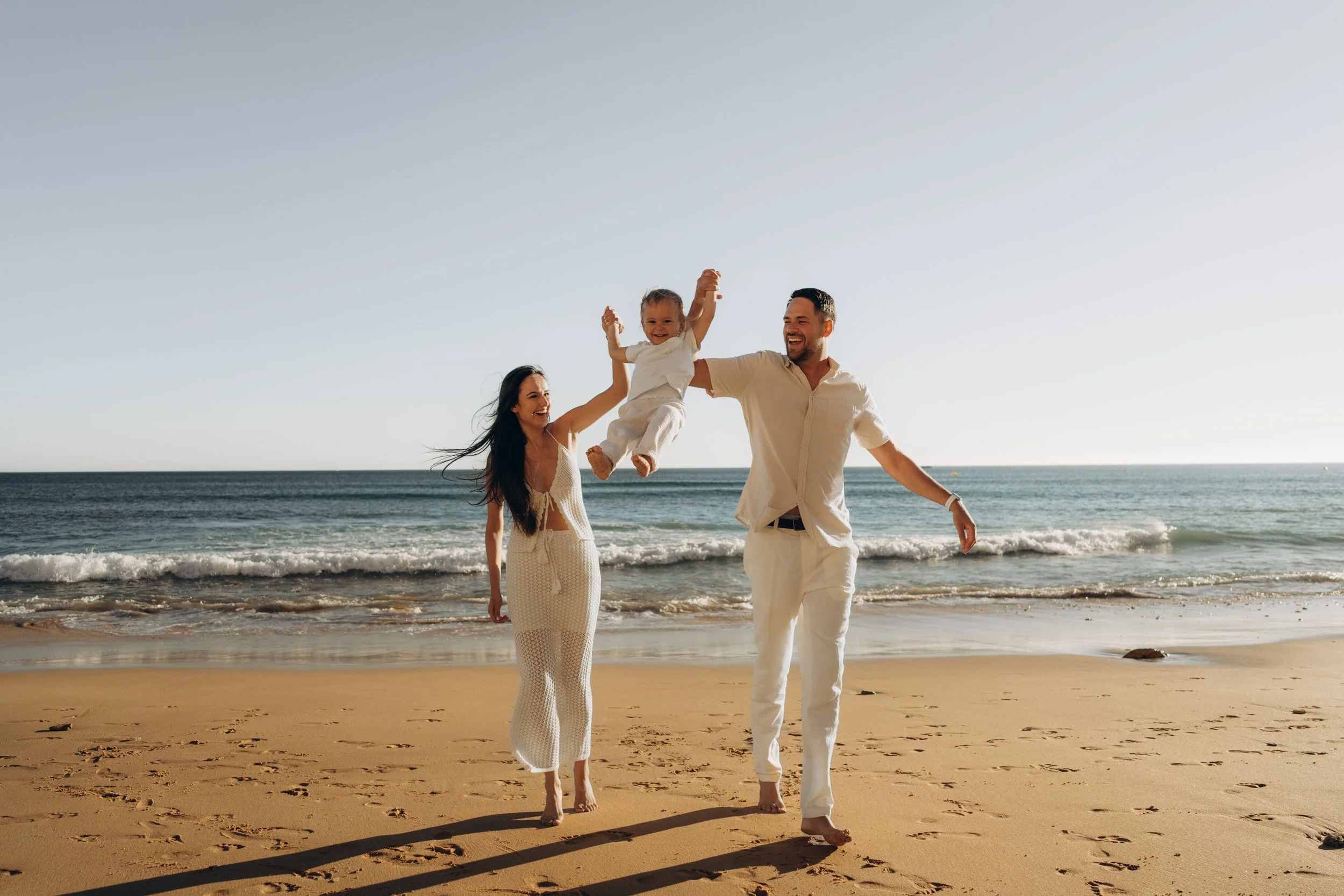 A family of three playing at the beach of Porto do Mòs, in the Algarve. Portugal