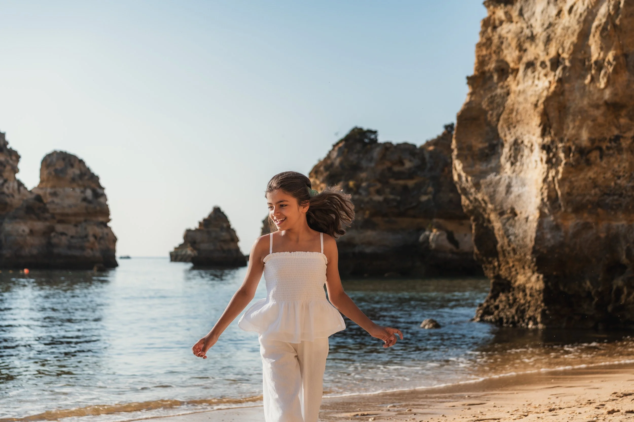 Girl walking on the beach during a family photoshoot at Praia do Camilo in Algarve.