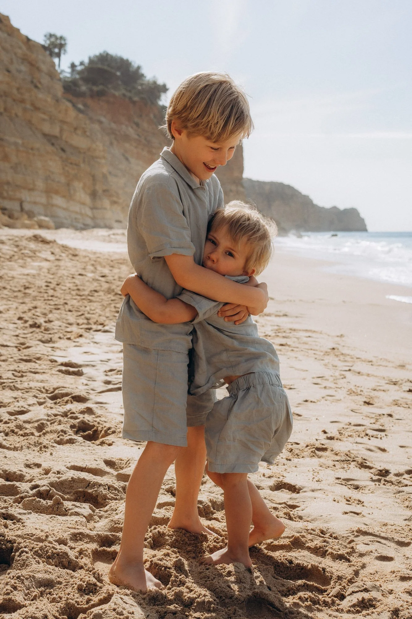 Two brothers hugging on Algarve beach at golden hour, candid children photography Algarve