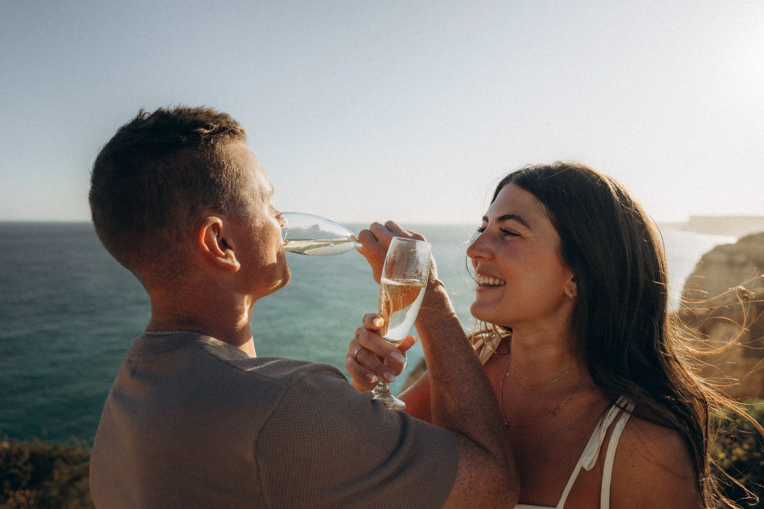 Pure emotion — tight embrace with the ocean horizon behind. Authentic Algarve proposal photography.