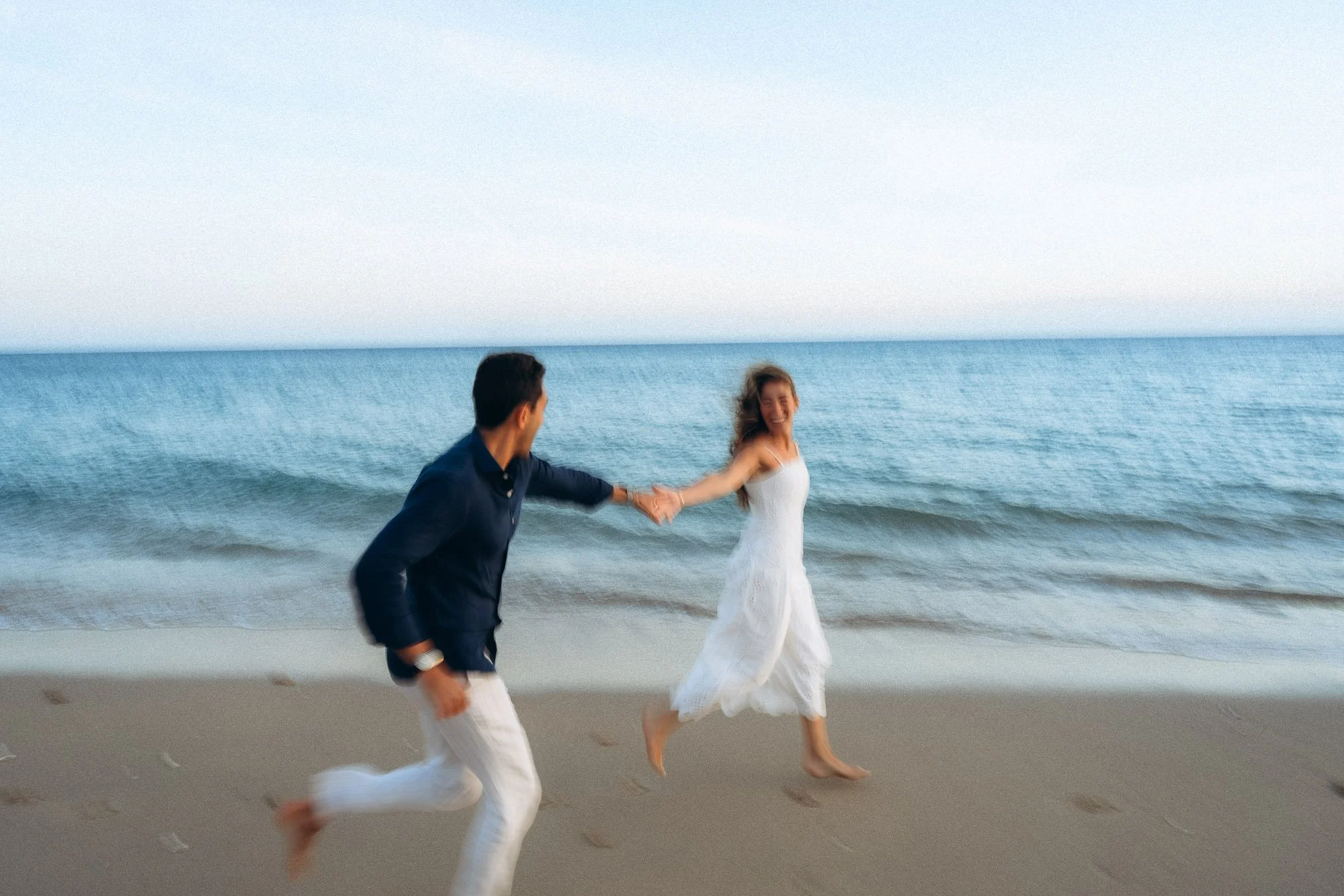 Couple running and laughing on Algarve beach at dusk, motion blur, cinematic couple photography Portugal