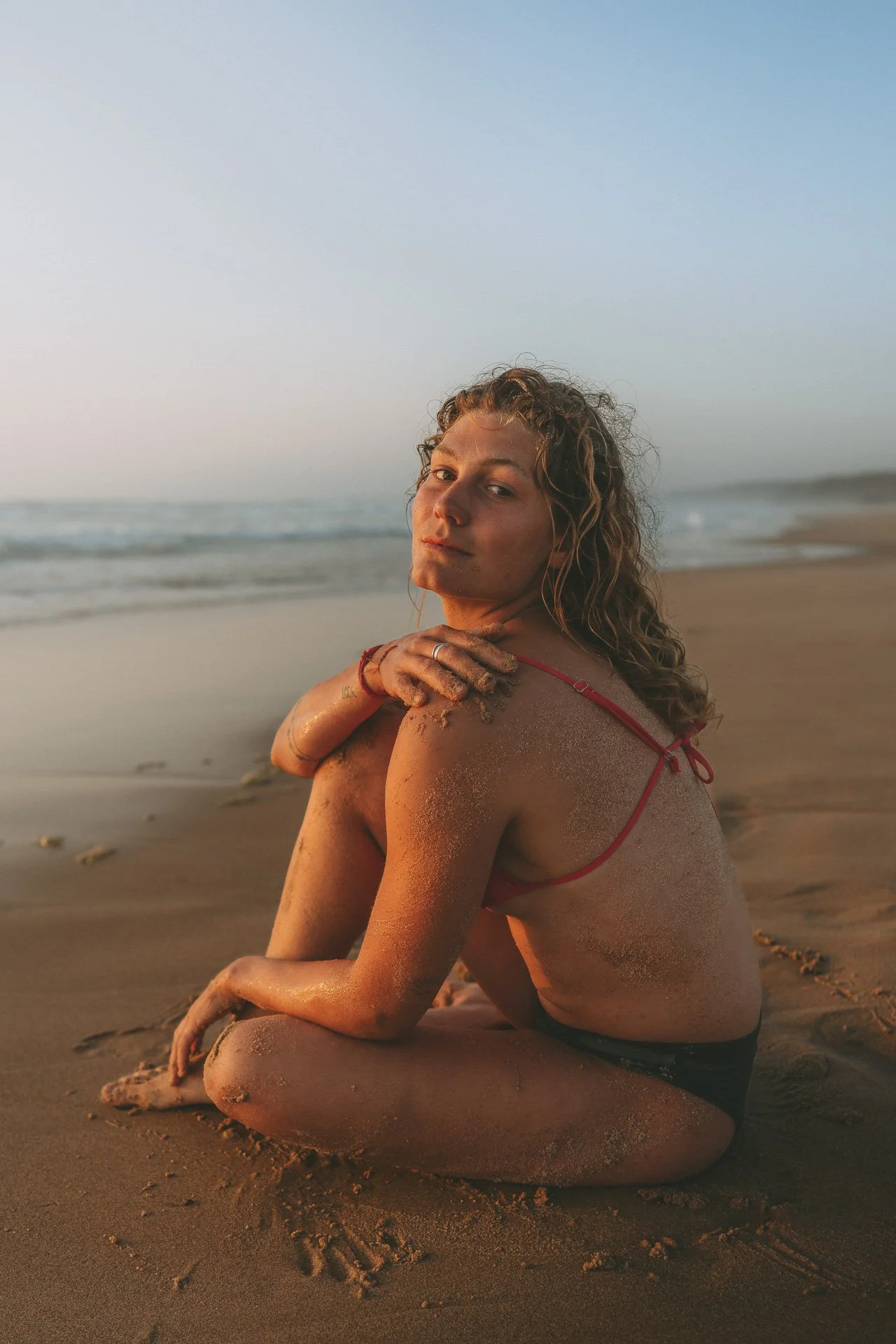 Intimate beach portrait at Bordeira Beach, Algarve. Bare skin, warm tones and a calm connection with the ocean landscape.