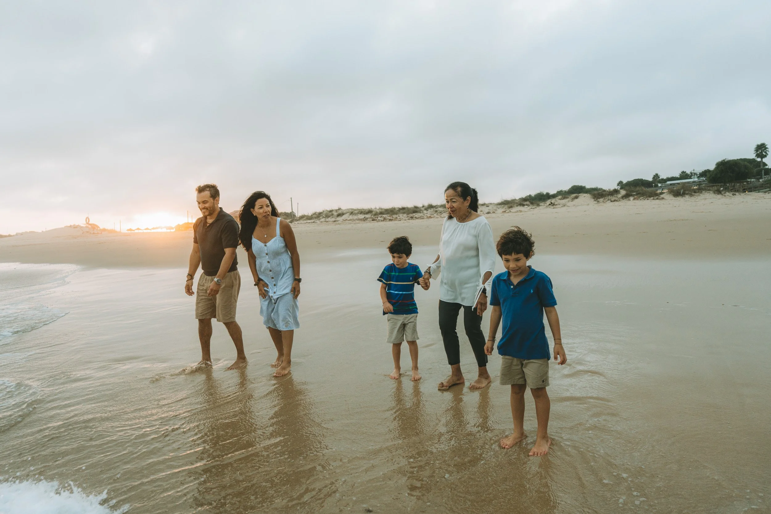 Parents and children sharing a genuine moment of laughter, photographed in a calm and unforced way on the beach.