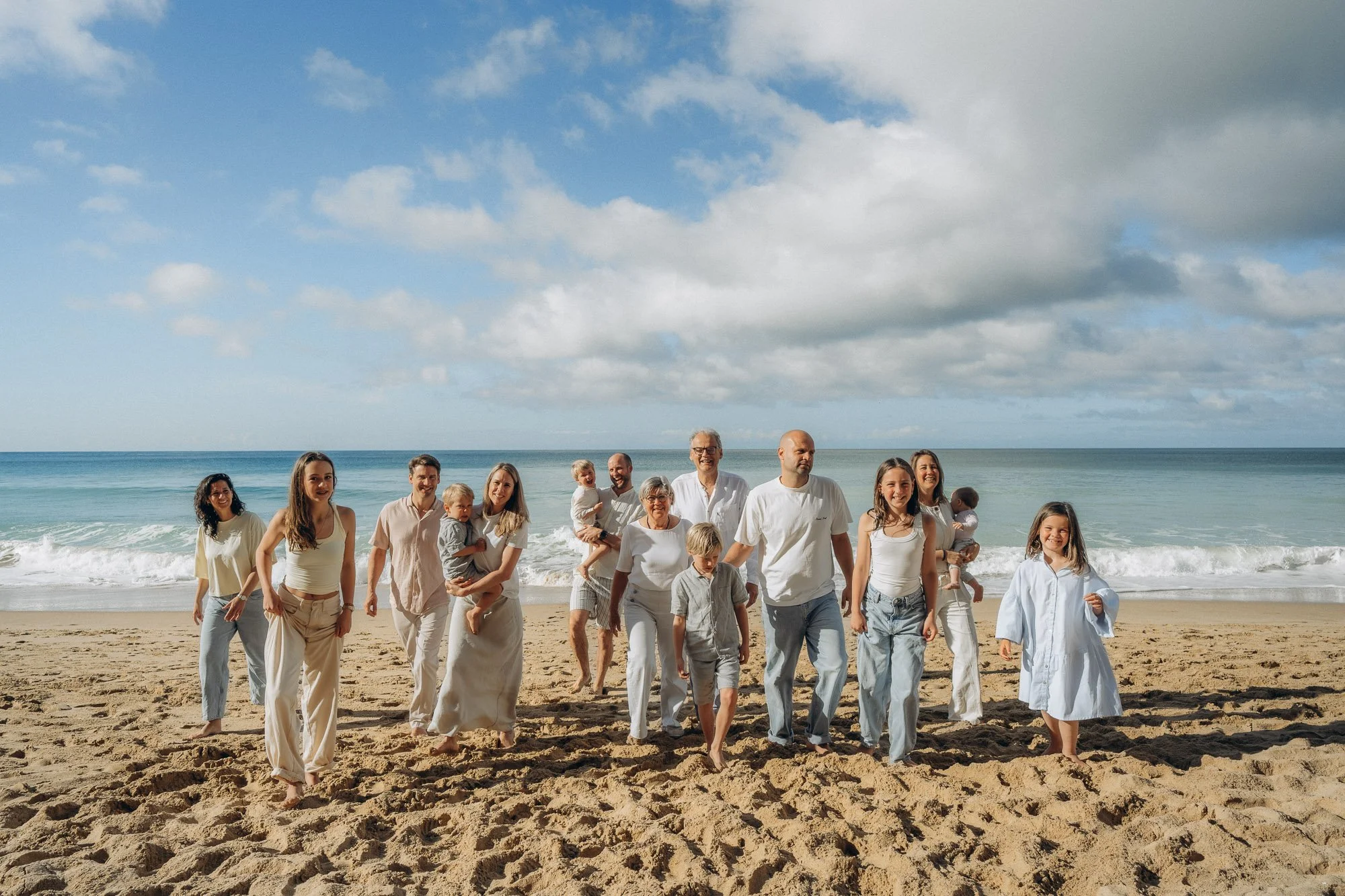 Extended family walking on Algarve beach with ocean behind, large family photography session Portugal