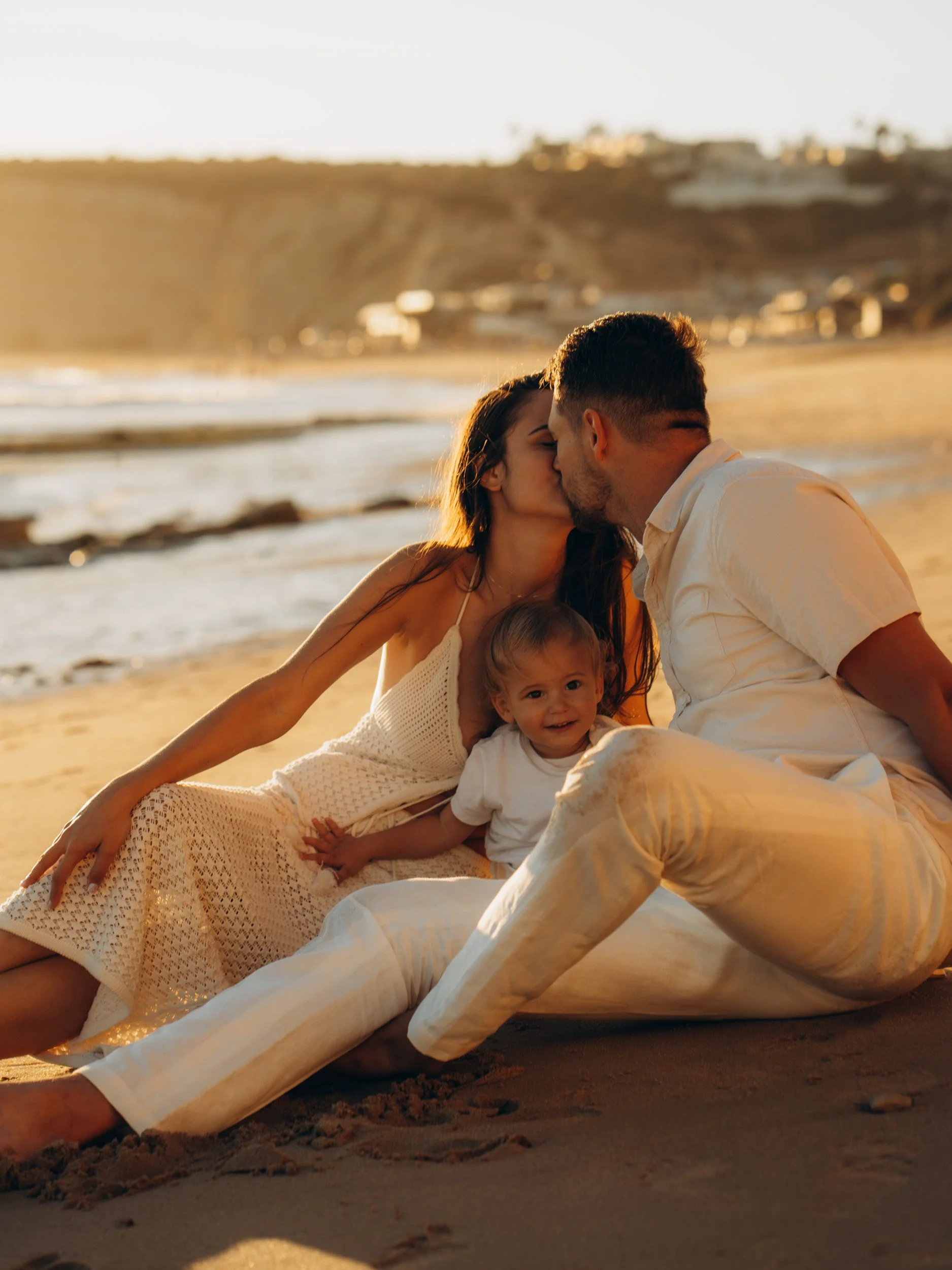 Parents kissing their child during golden hour family photos in the Algarve
