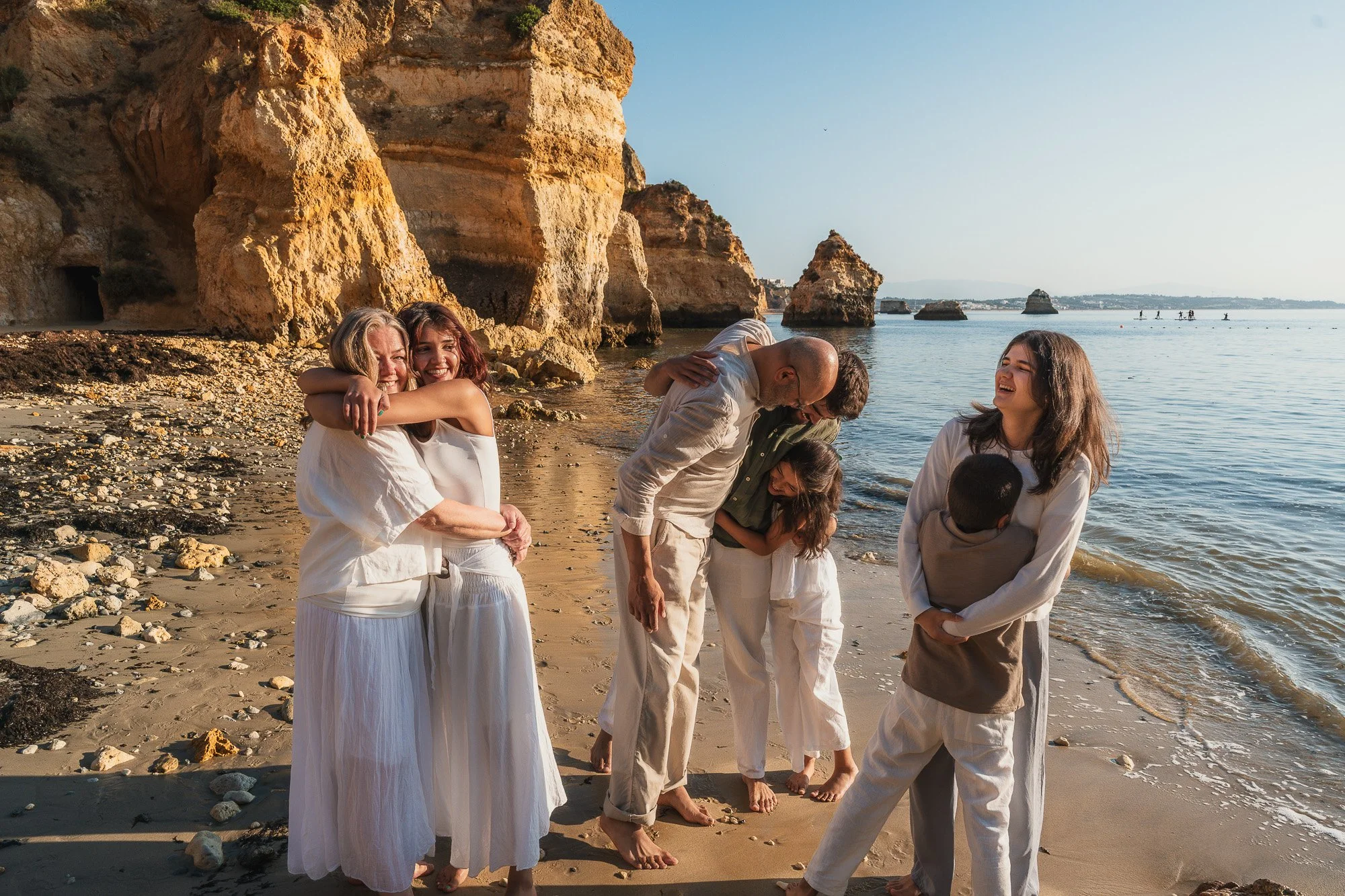 Family of 7 hugging along the shore at Praia do Camilo, Lagos, Algarve.