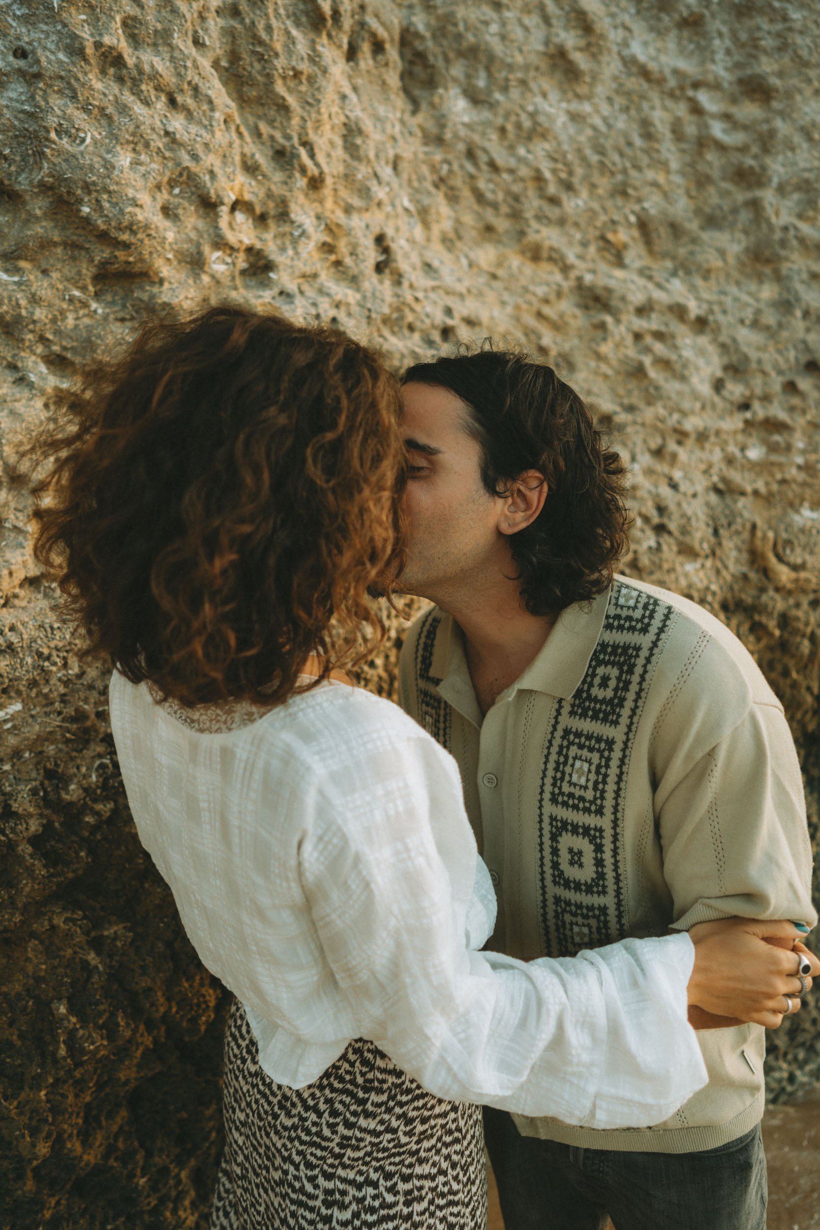 Candid laughter captured during a romantic beach photoshoot in Alvor, natural movement and wind in the hair at golden hour.