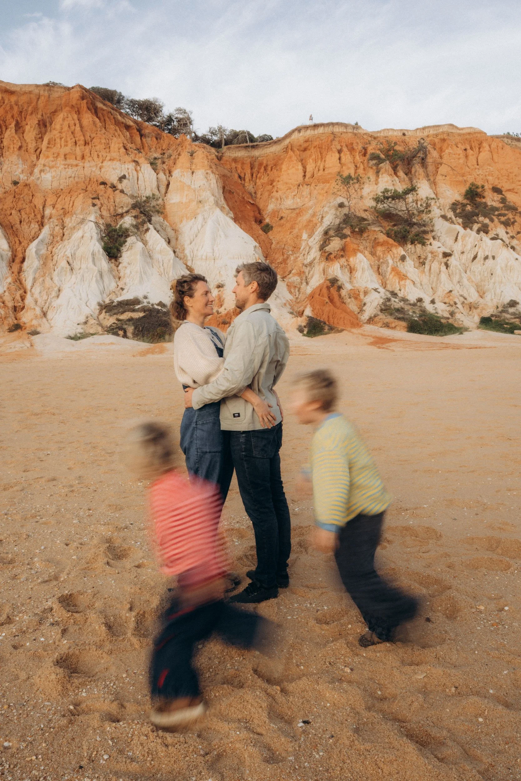 Parents playing together during family photoshoot at Falésia beach Algarve cliffs background