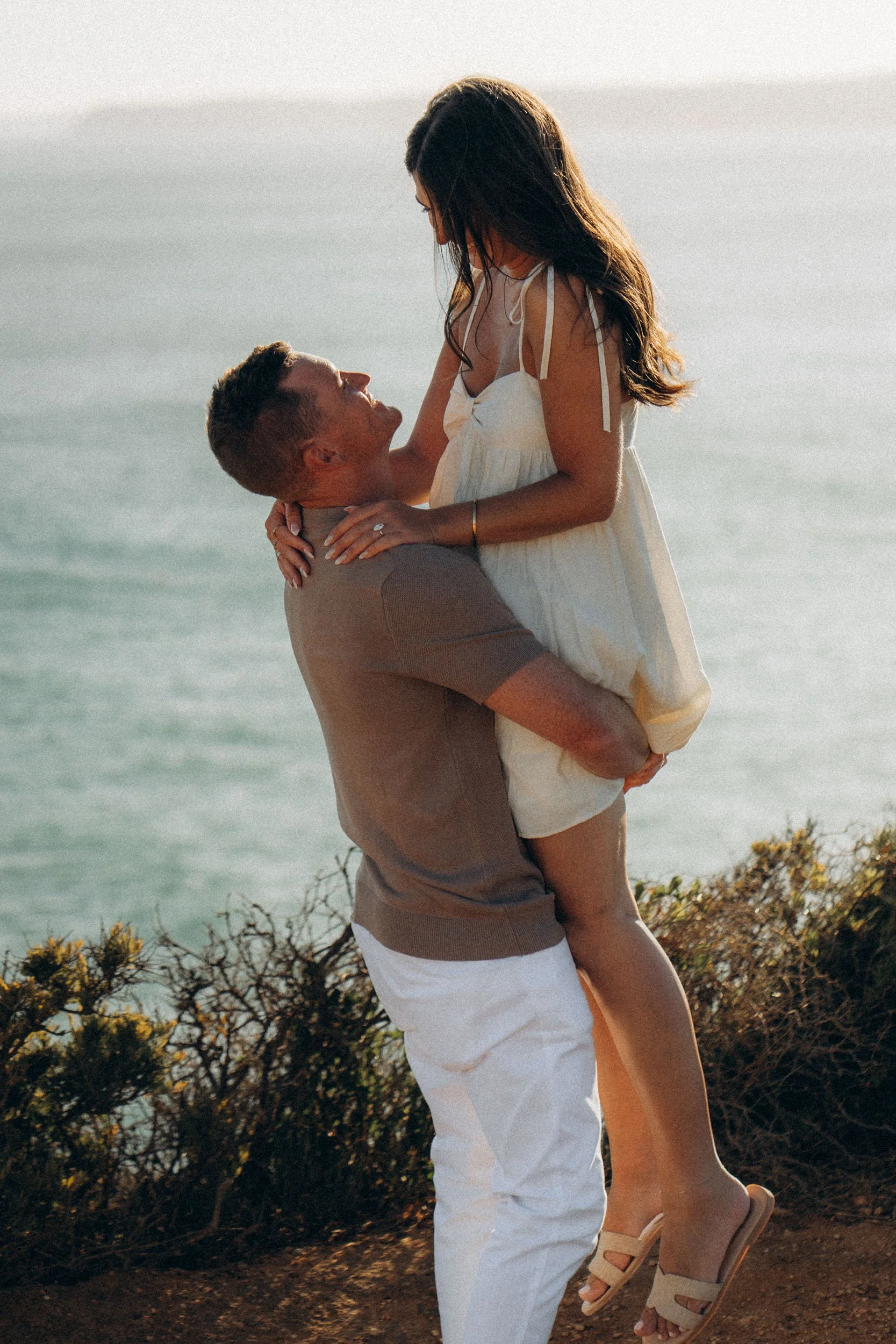 Spontaneous lift after the proposal. Movement, wind, connection. The Algarve cliffs blurred softly behind them.