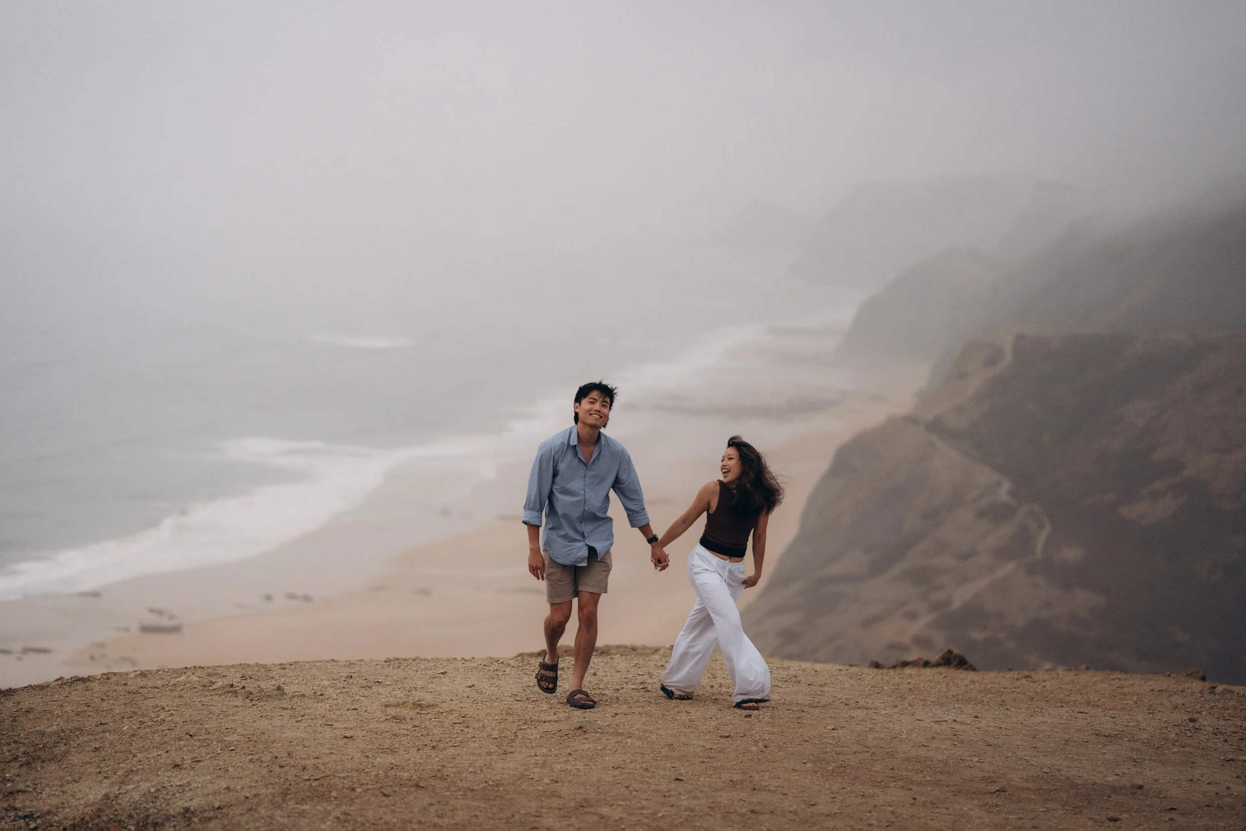 A couple walking along dramatic cliffs at Praia do Castelejo, showcasing scenic Algarve landscapes perfect for engagement and couple photoshoot locations.