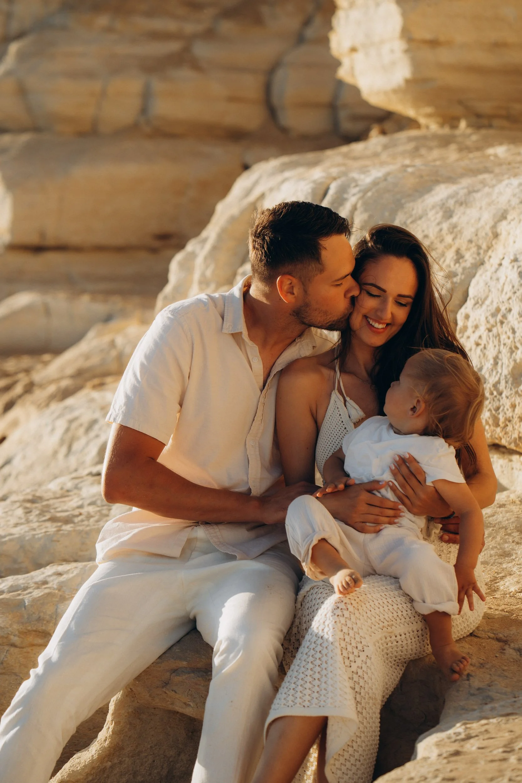 Parents embracing their child during a sunset family session on the Algarve cliffs
