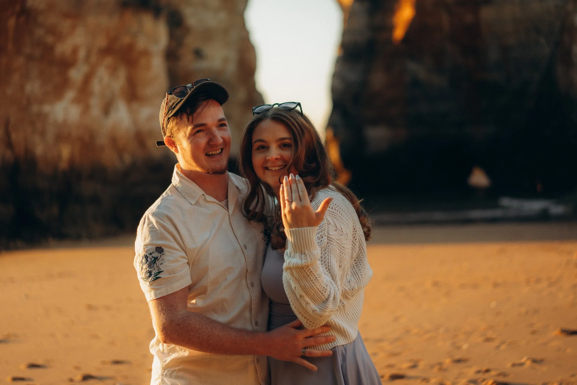 A couple celebrating engagement at Praia dos Estudiantes, Lagos showing the ring during a golden hour photoshoot