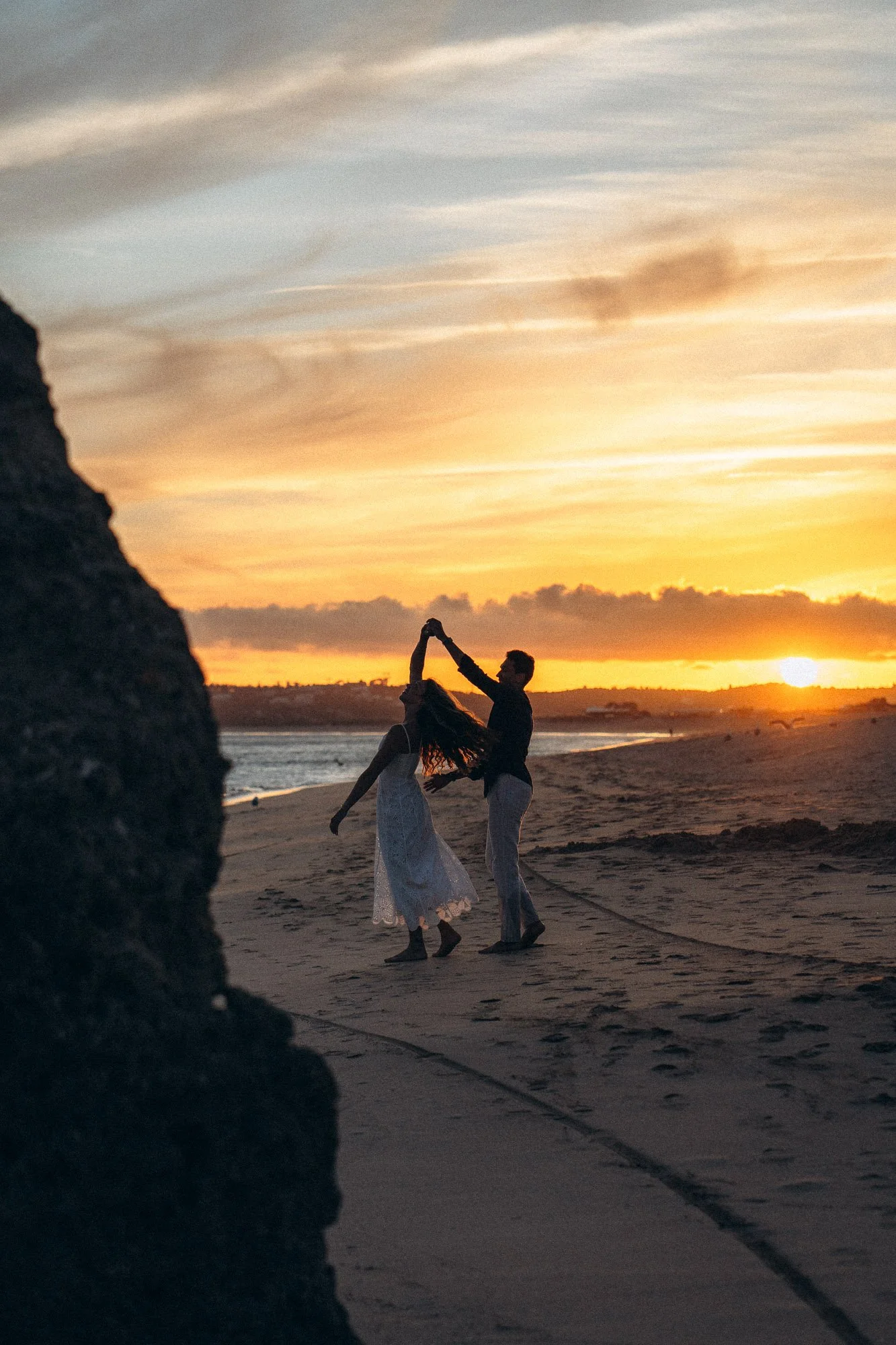 Couple dancing at sunset on Algarve beach, romantic silhouette against orange sky, couples photographer Portugal