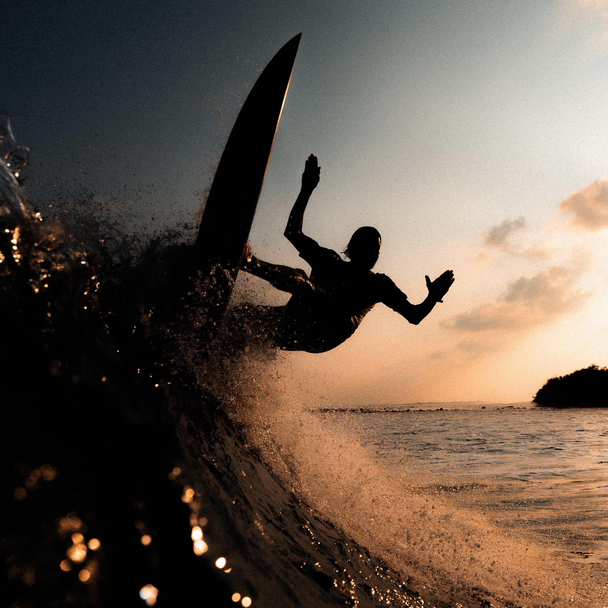 Silhouette of a person surfing on a wave at sunset