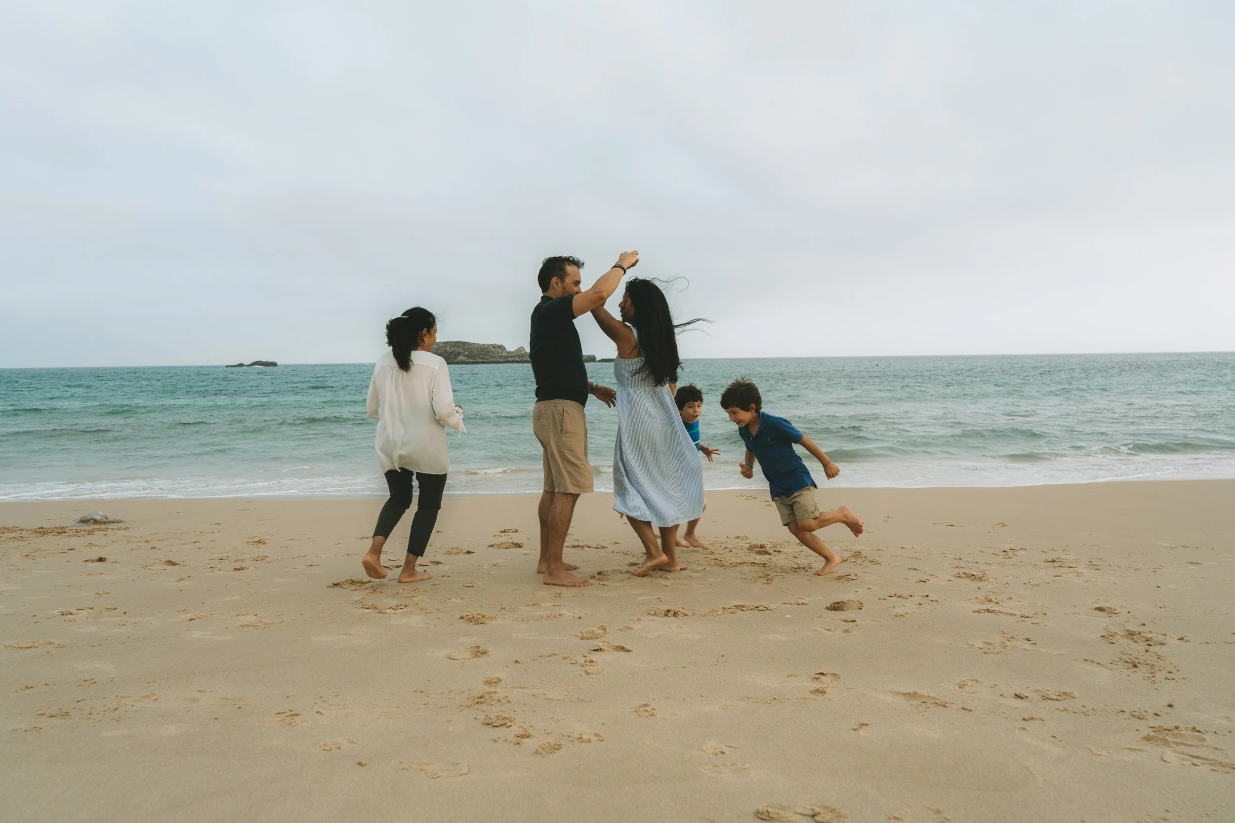 Family photoshoot at Praia do Martinhal, Sagres, with parents and children walking freely along the beach.