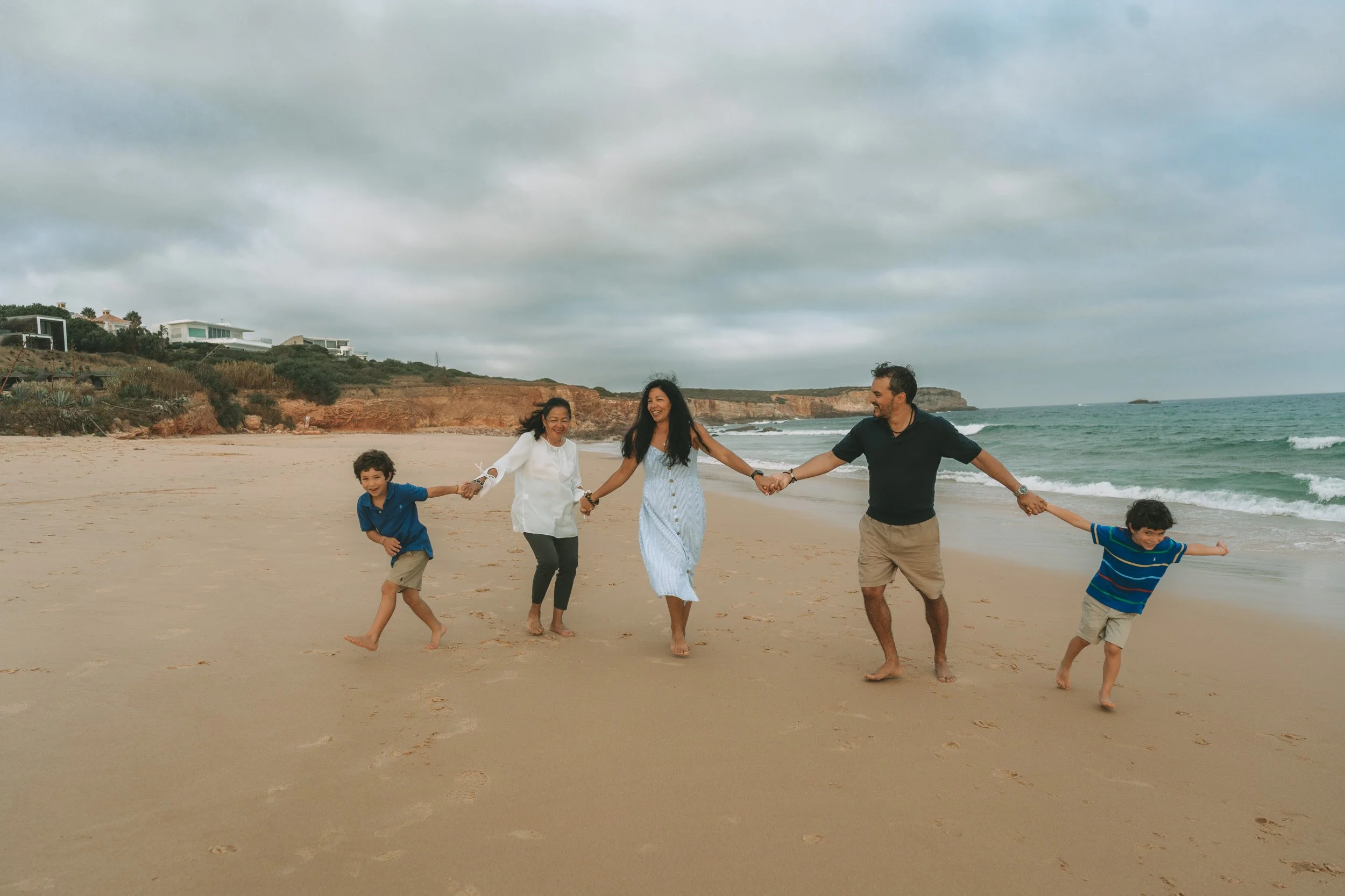 A family walking together along the shoreline at Praia do Martinhal, with open space and soft light creating a relaxed and natural feeling.