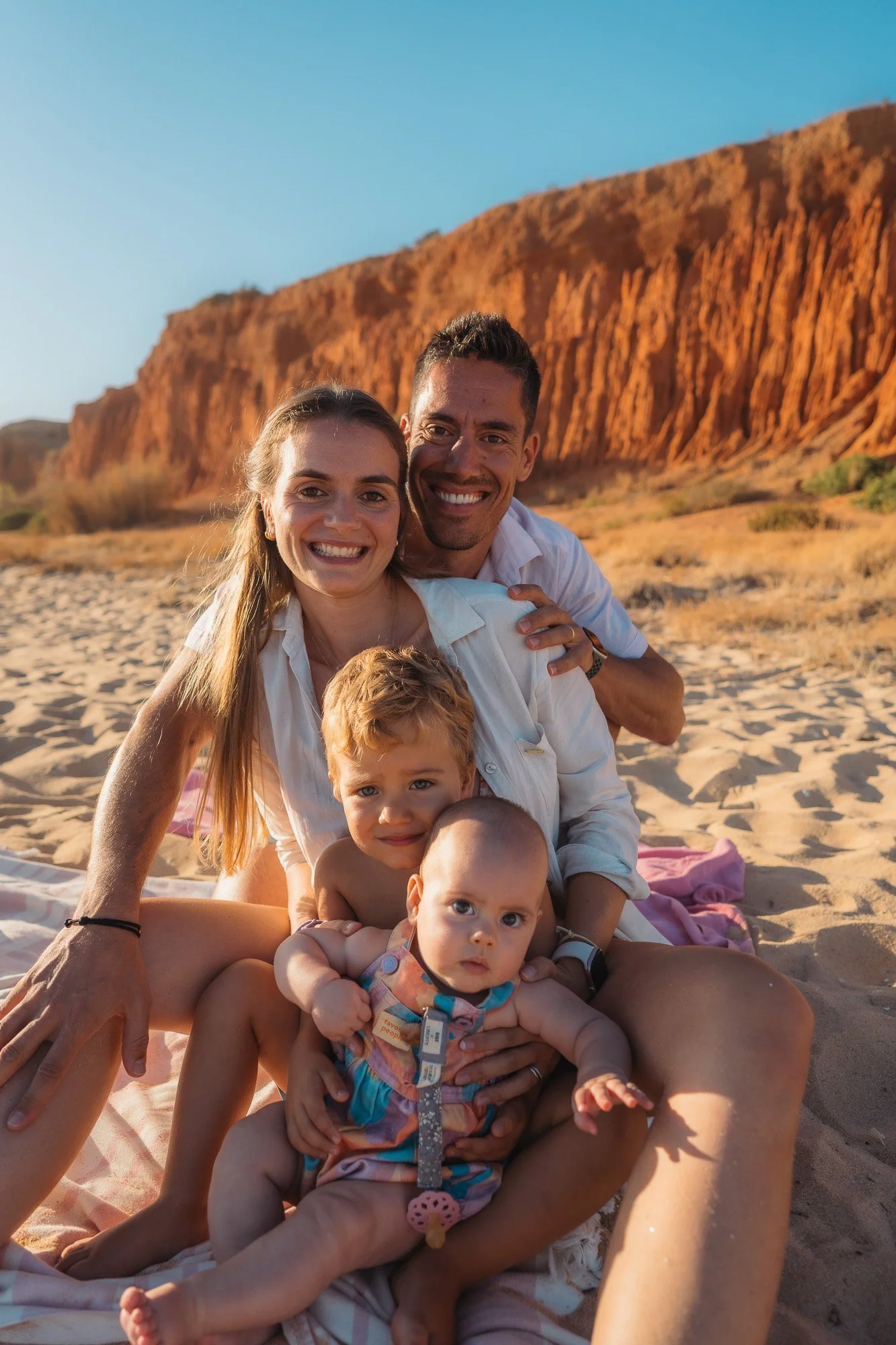 Natural portrait of a family of 4 on a cliff at golden hour in the Algarve.