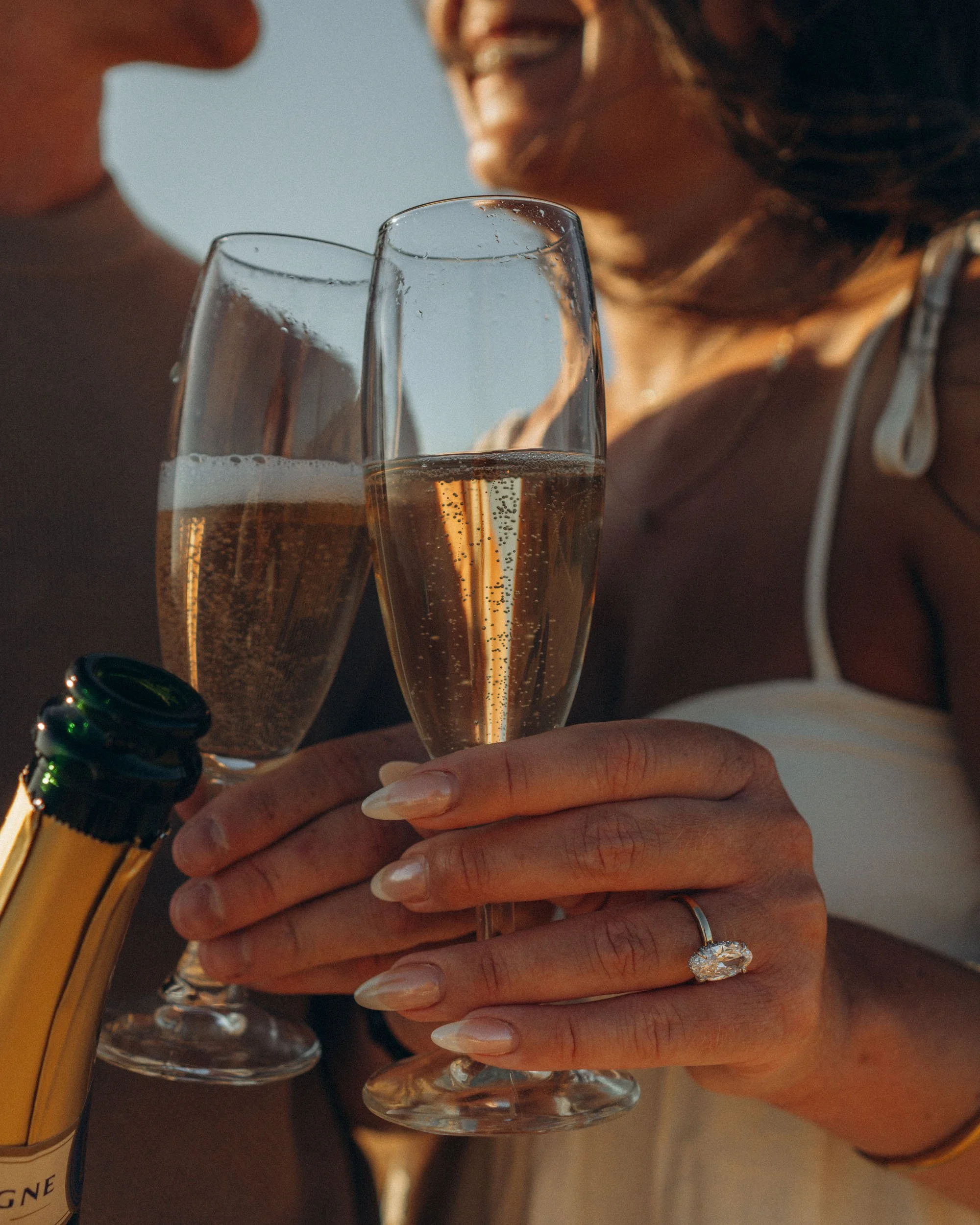 Close-up portrait highlighting connection, ring detail and sunset light shaping the faces.