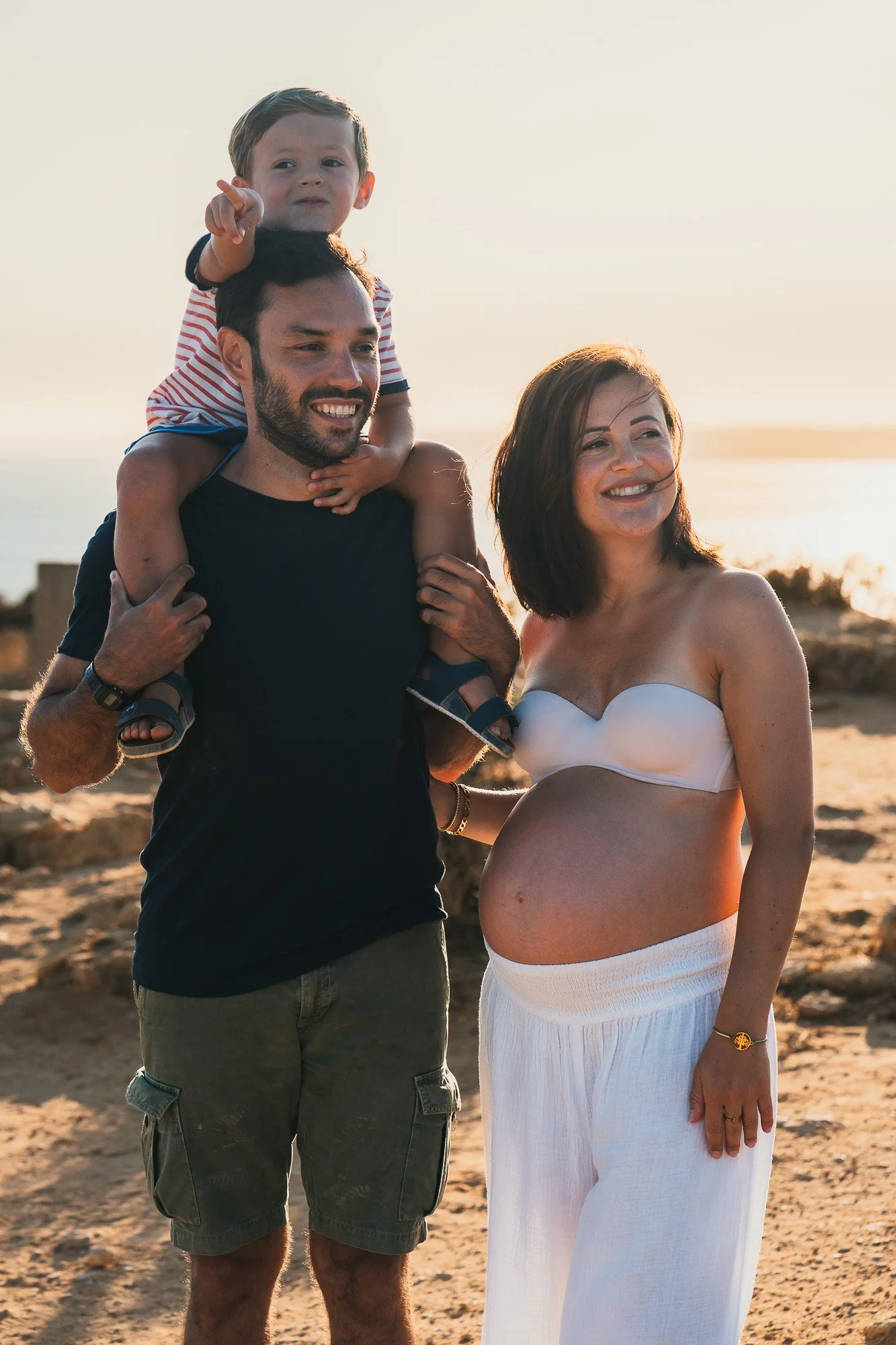 Expectant mother with partner and child enjoying the cliffside views at Ponta da Piedade, Lagos Algarve.