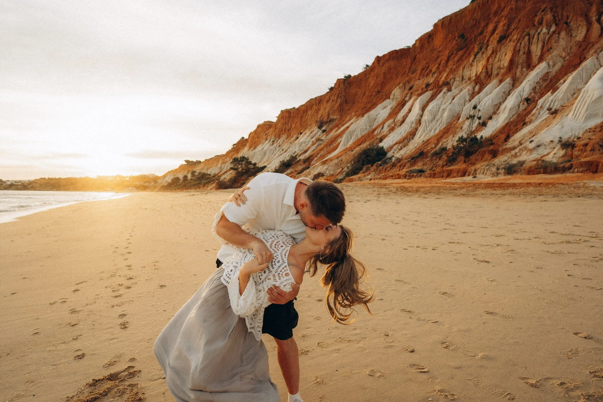 Couple dip kiss on Praia da Falésia Algarve, red and orange striped cliffs at sunset, couples photographer