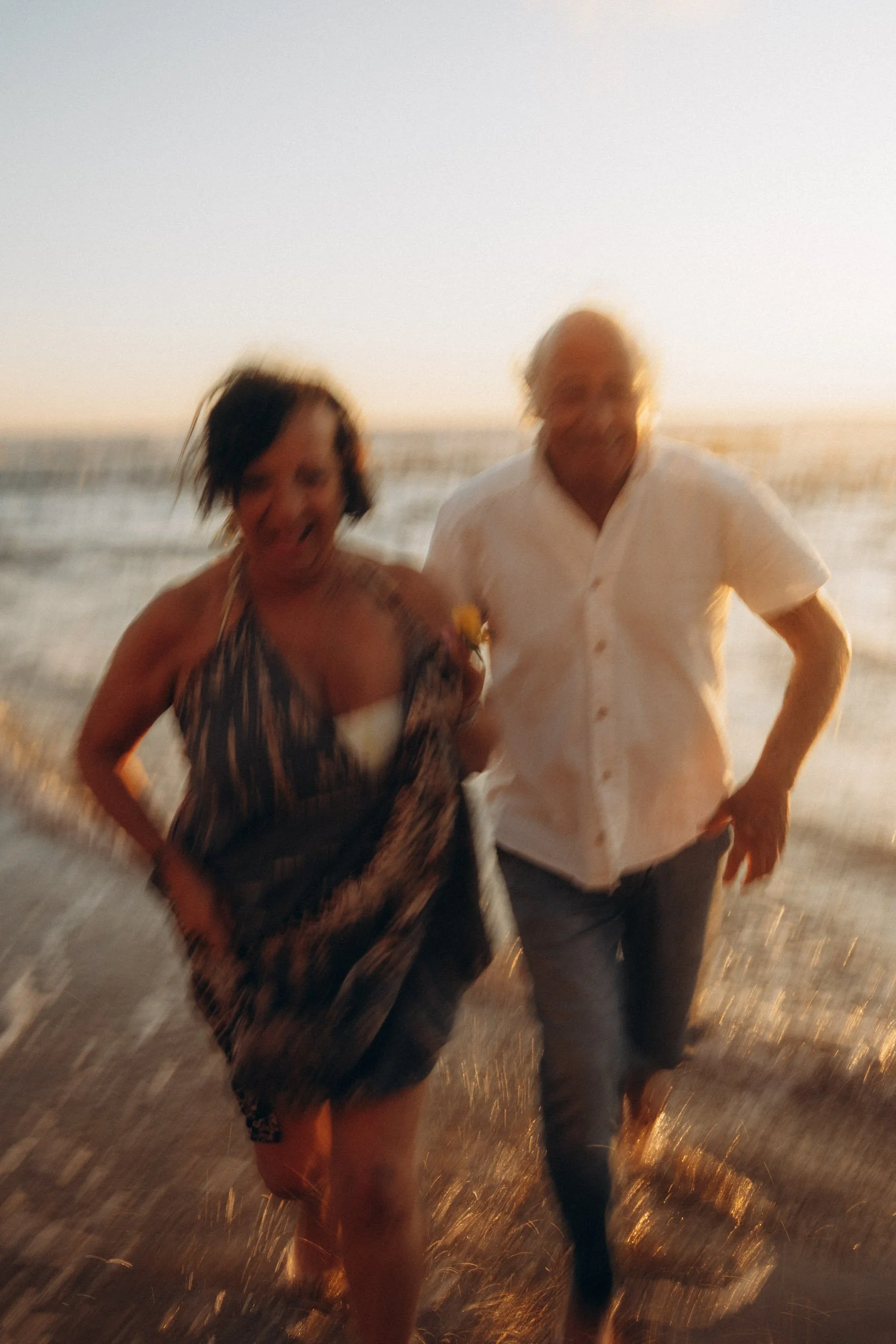 Cinematic couple running towards the camera at Praia do Tonel, capturing movement and emotion.