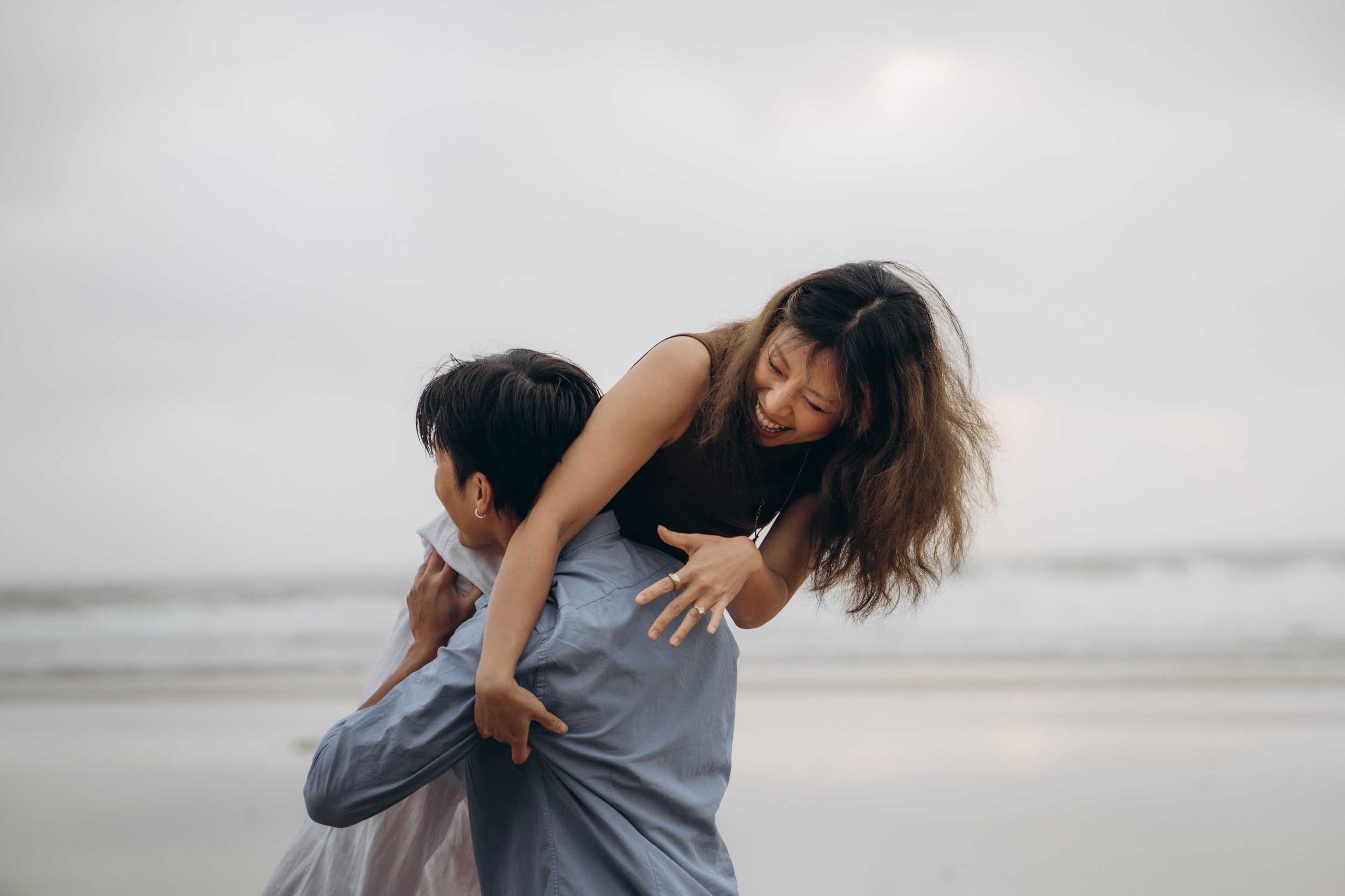 Playful couple photography session on a wild Algarve beach, highlighting movement and spontaneity, part of a relaxed destination photoshoot experience.