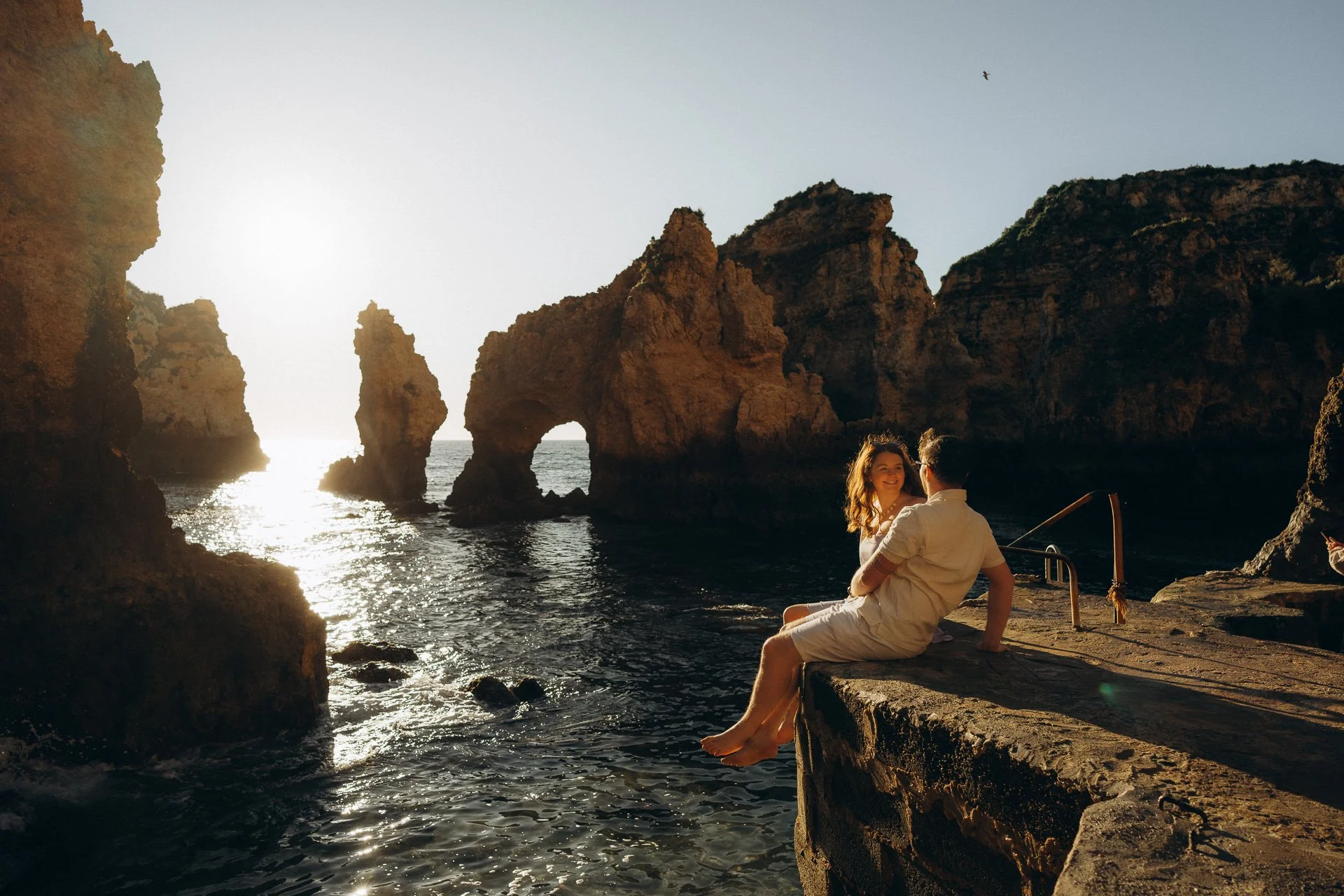 Couple sitting on cliffs at Ponta da Piedade during sunset photoshoot in Lagos Algarve