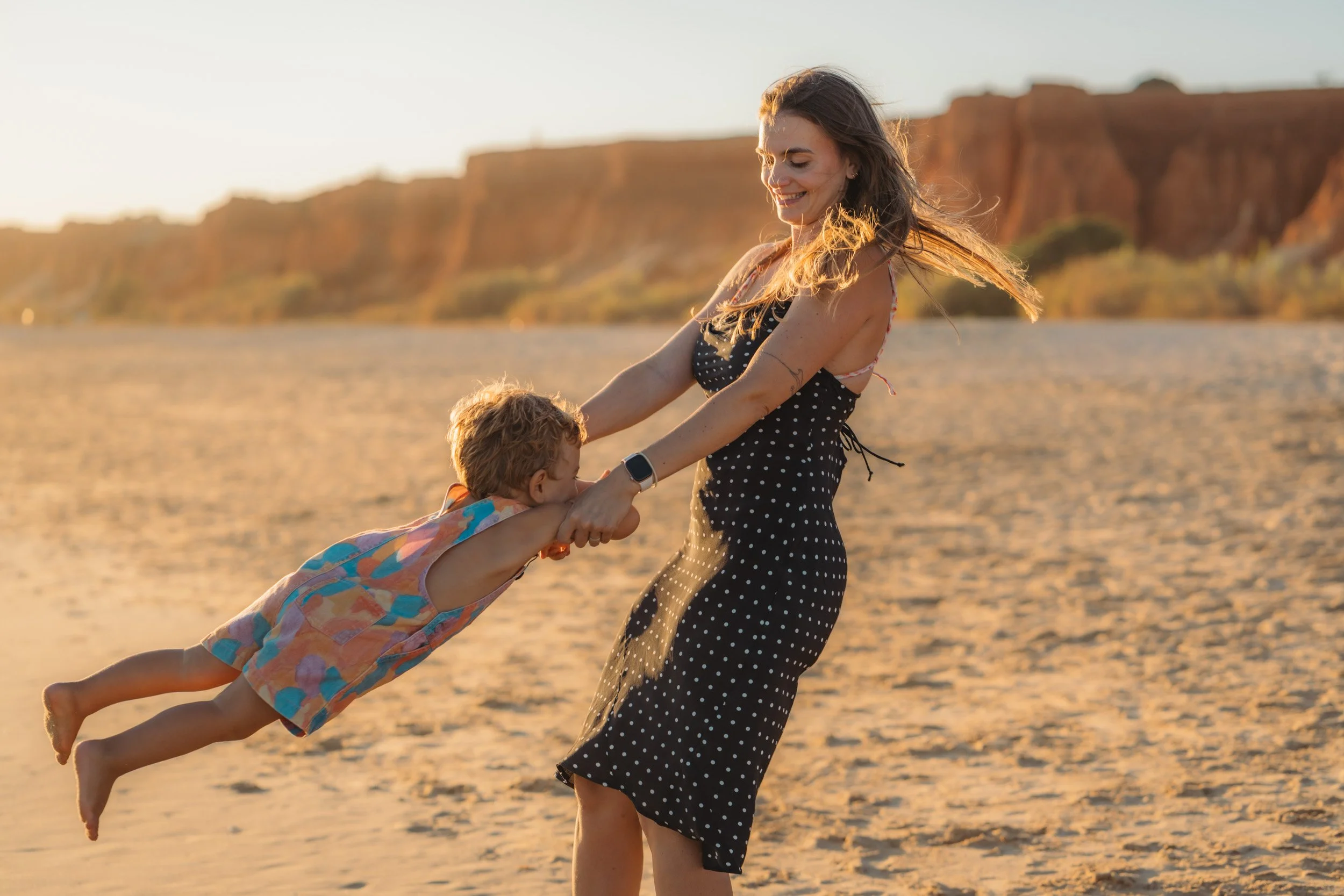 Fun family photoshoot Algarve — mother lifting children at Praia da Falésia Albufeira