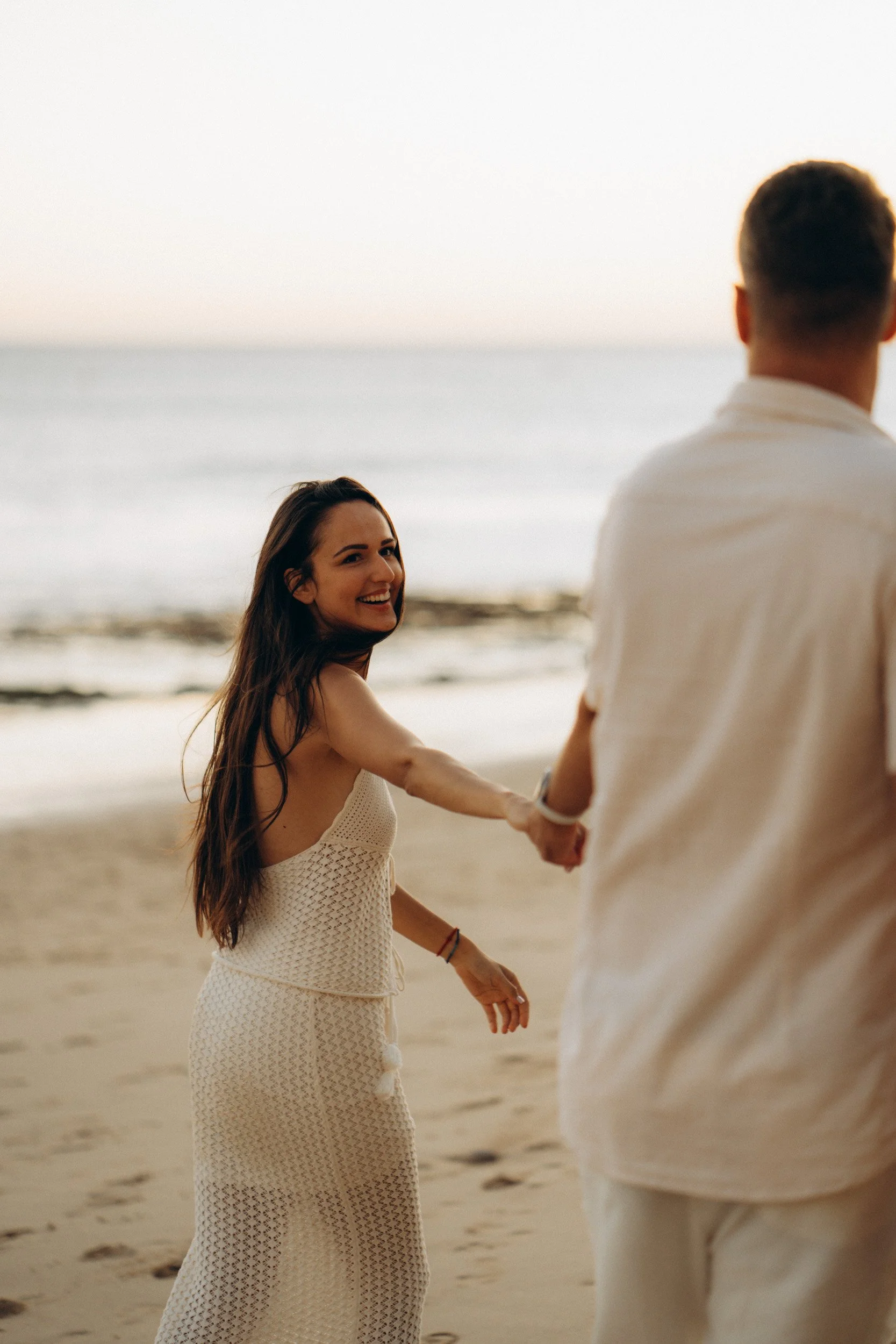 Woman leading partner along shoreline — romantic beach photos Algarve Portugal