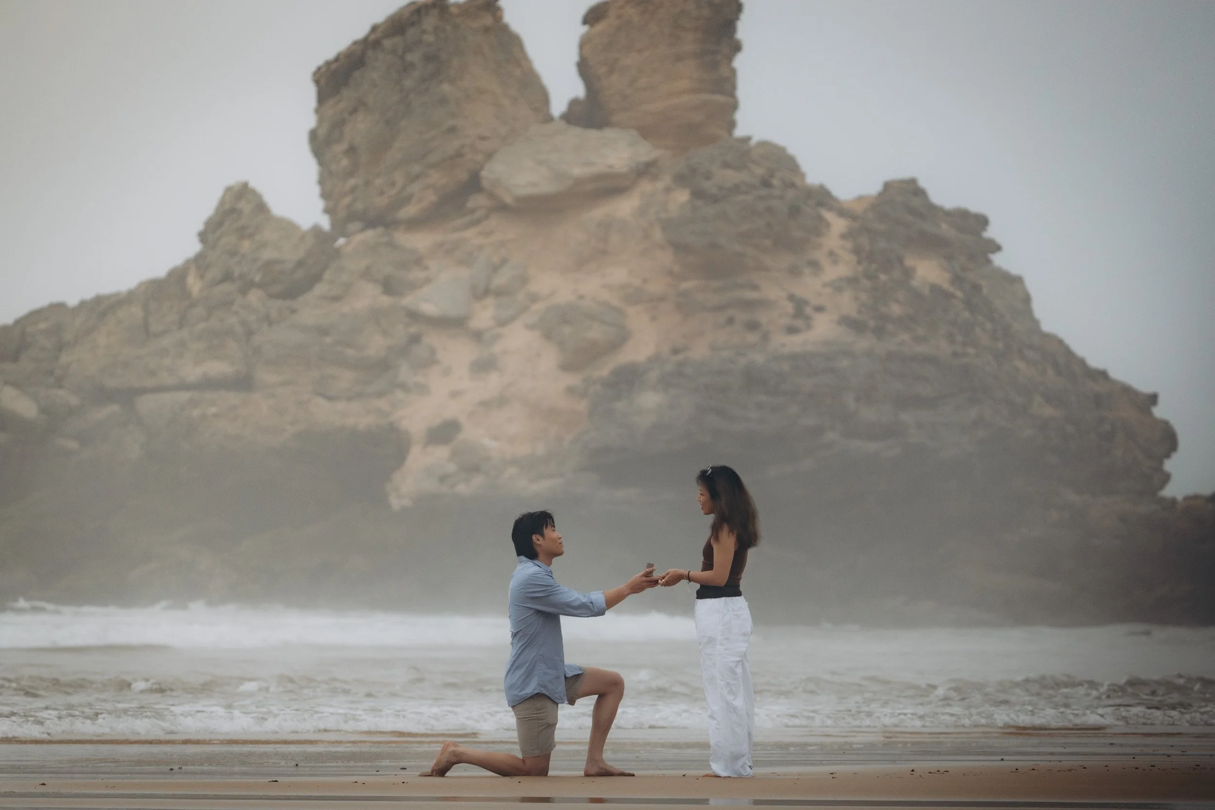 Beach proposal moment captured in the Algarve during a surprise engagement photoshoot, documenting genuine reactions and storytelling imagery.