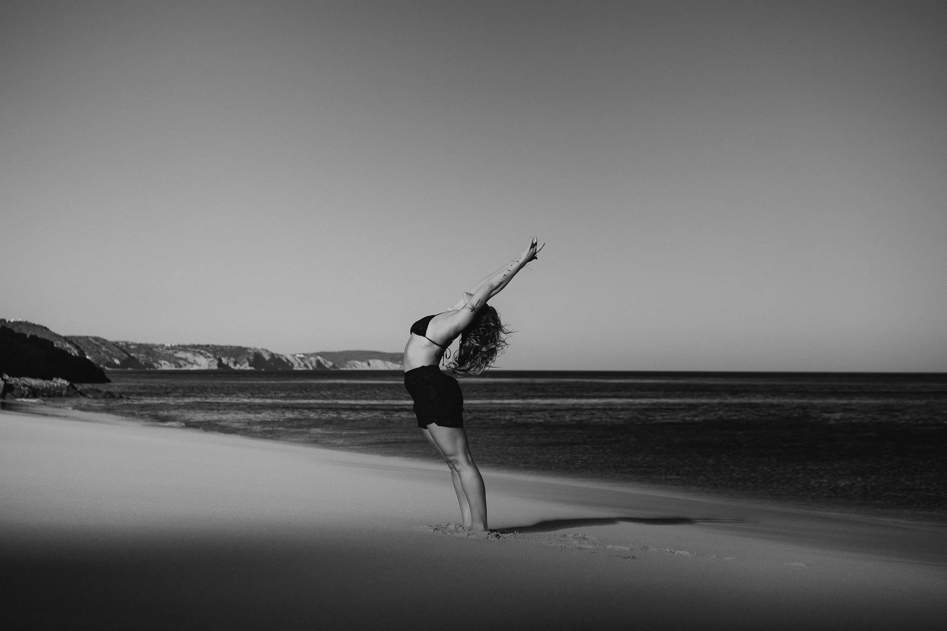 Yoga session on a quiet Algarve beach, framed by warm cliffs and soft evening light.
