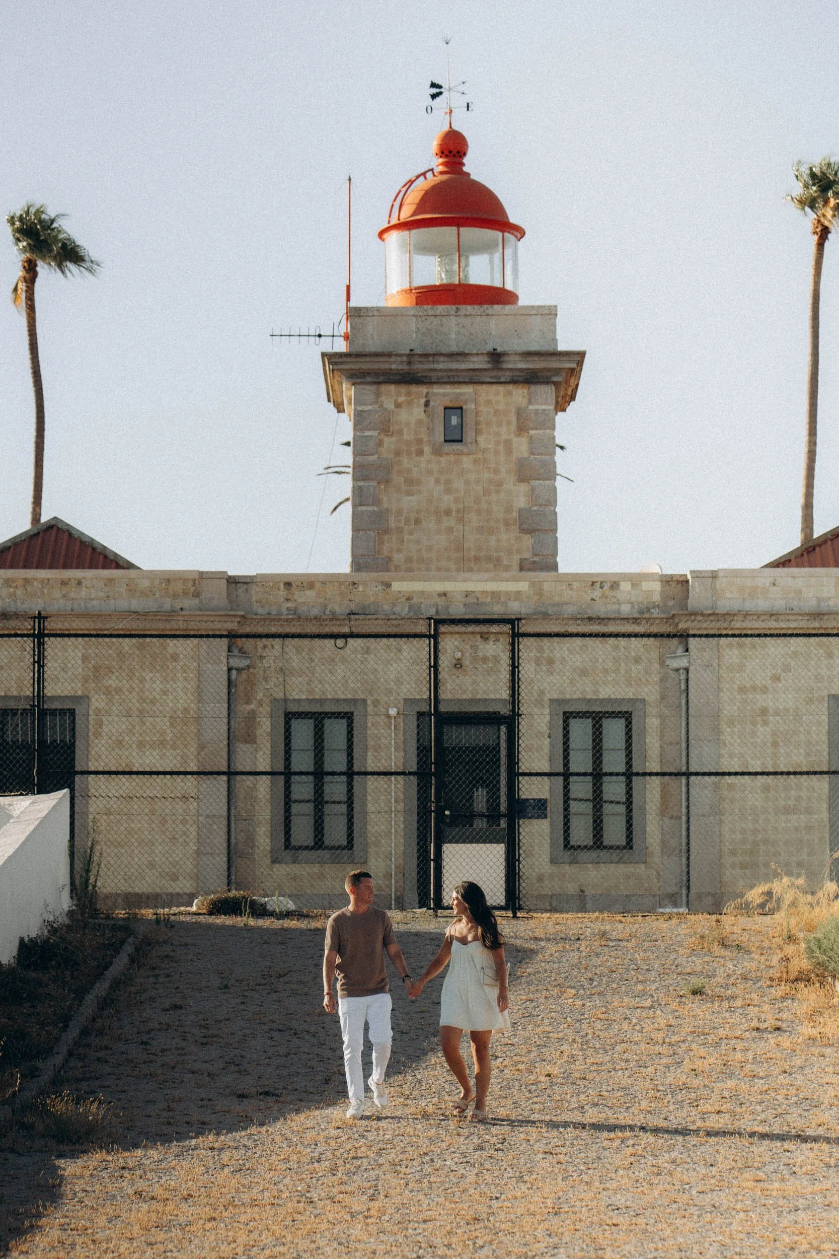 Walking hand in hand near the Ponta da Piedade lighthouse. Soft sunset tones, relaxed movement, effortless Algarve atmosphere.
