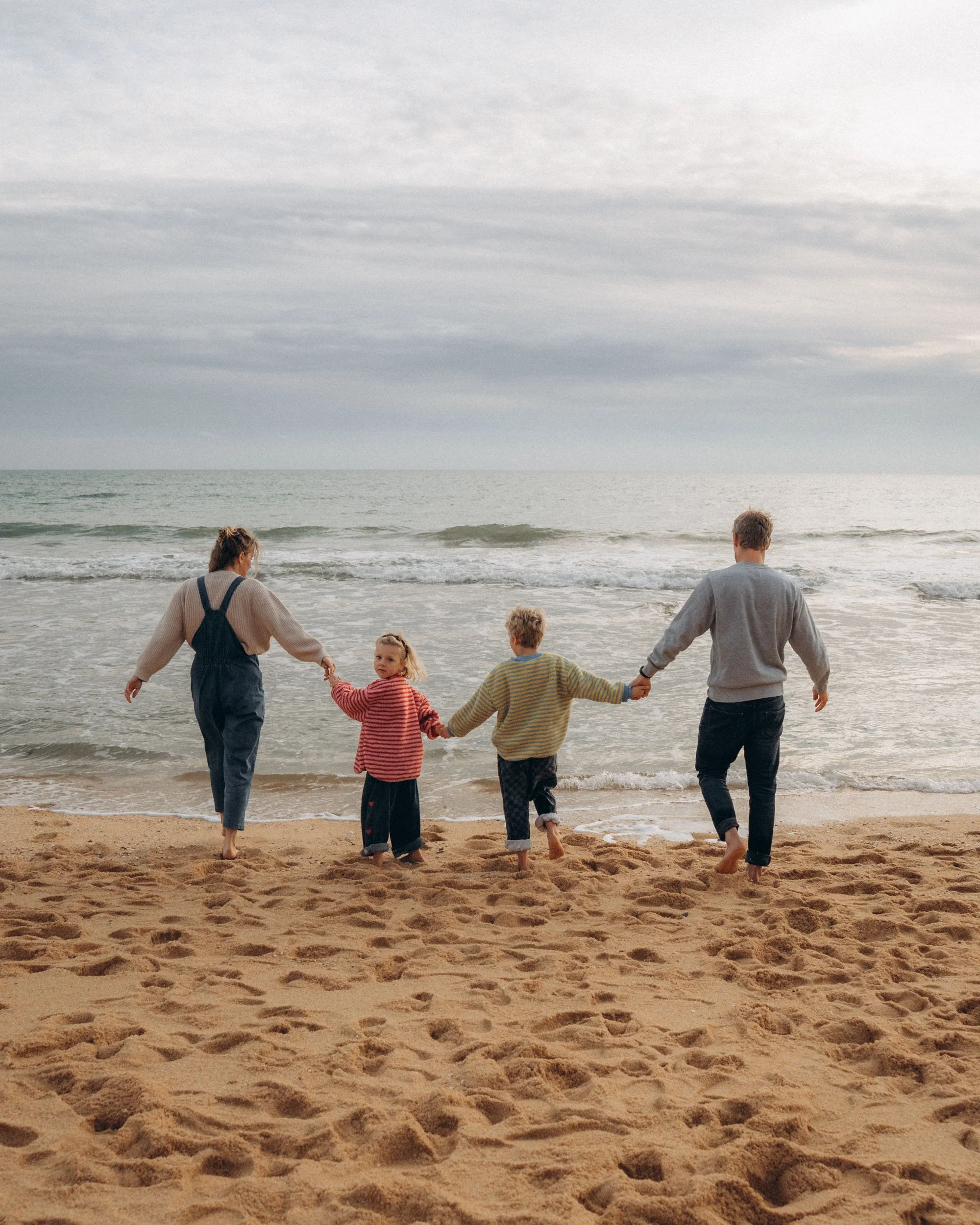 Family walking toward ocean during Praia da Falésia family photoshoot Algarve
