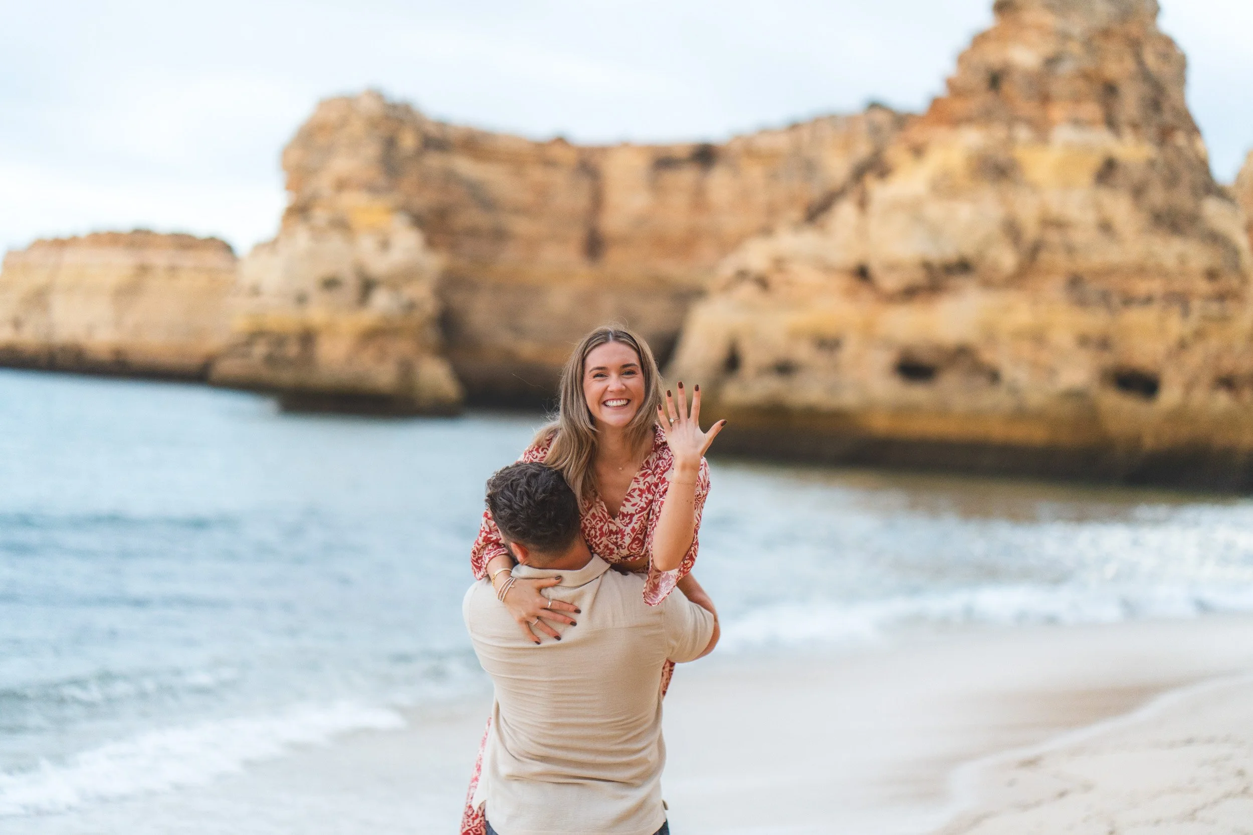 Just engaged moment on Praia da Marinha beach, Algarve, with the bride-to-be proudly showing her ring against the limestone cliffs.