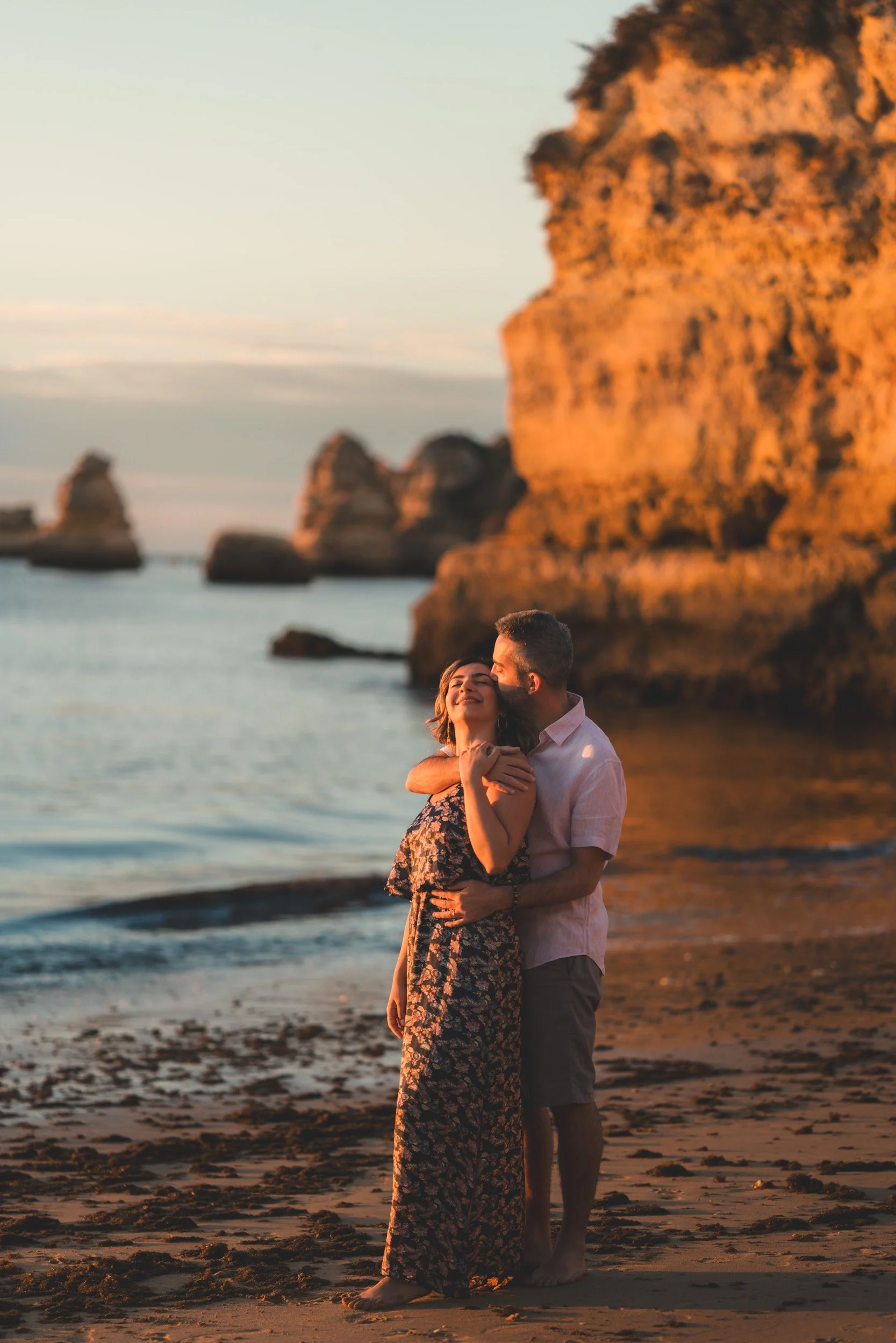 Intimate embrace near the cliffs of Lagos, romantic couple photoshoot at Praia Dona Ana during golden hour.
