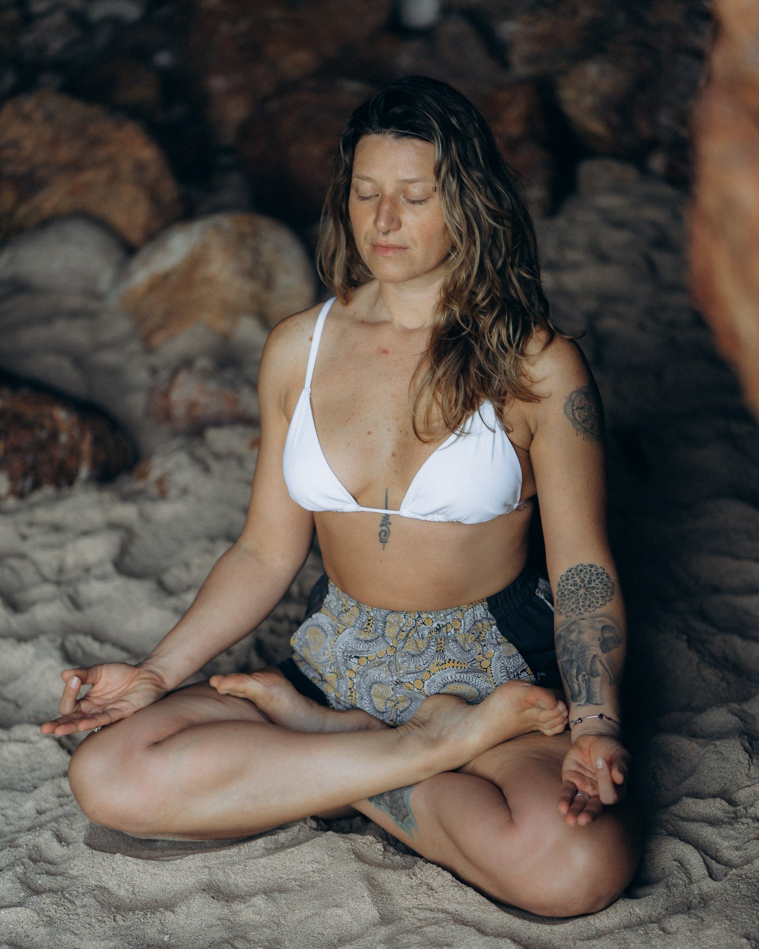Meditative yoga pose inside a sea cave, using natural light and raw textures of the Algarve coast.