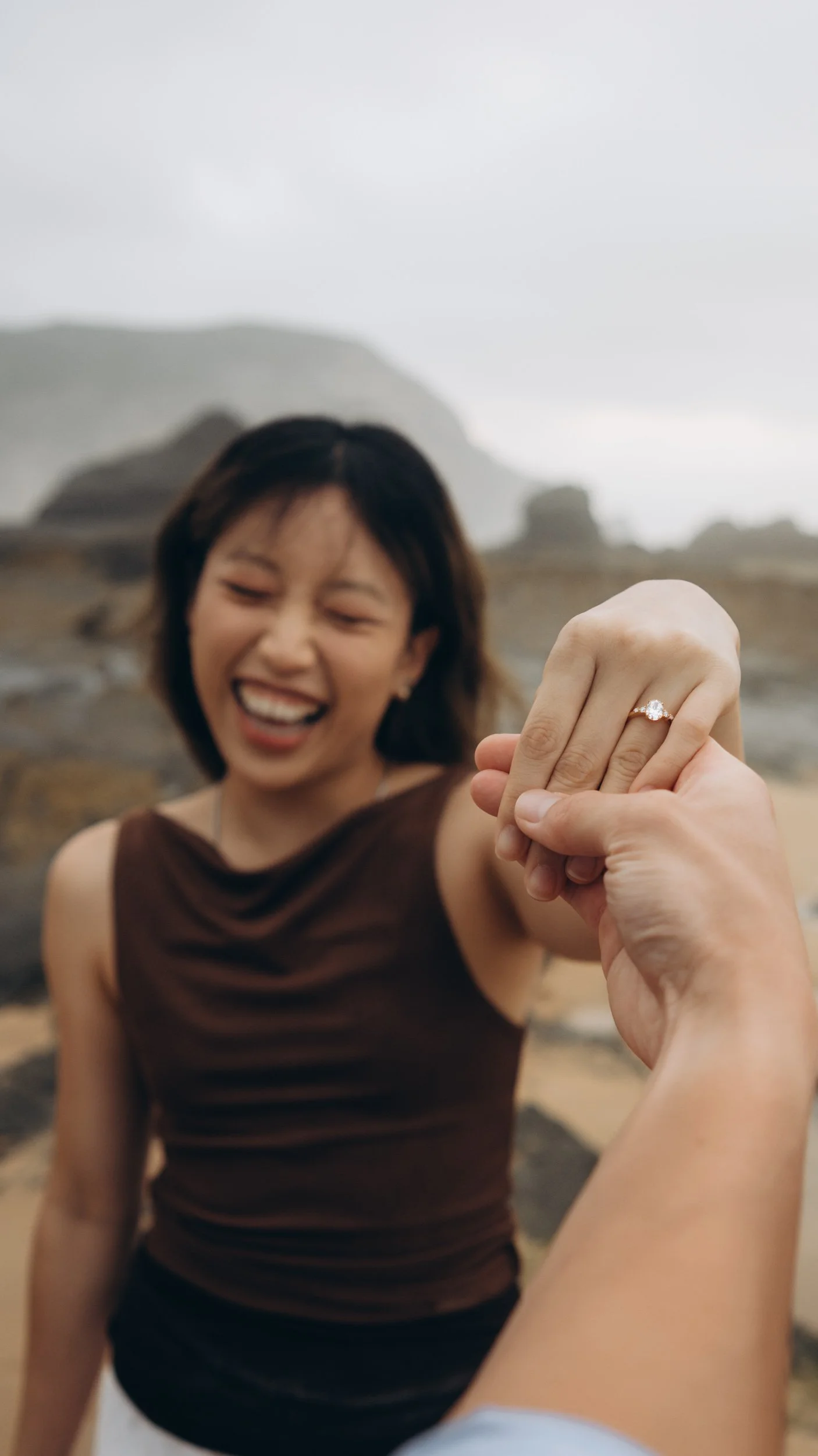 Close emotional moment during a surprise proposal photoshoot at Praia do Castelejo, Algarve, capturing the engagement ring and authentic reaction in a natural beach setting.
