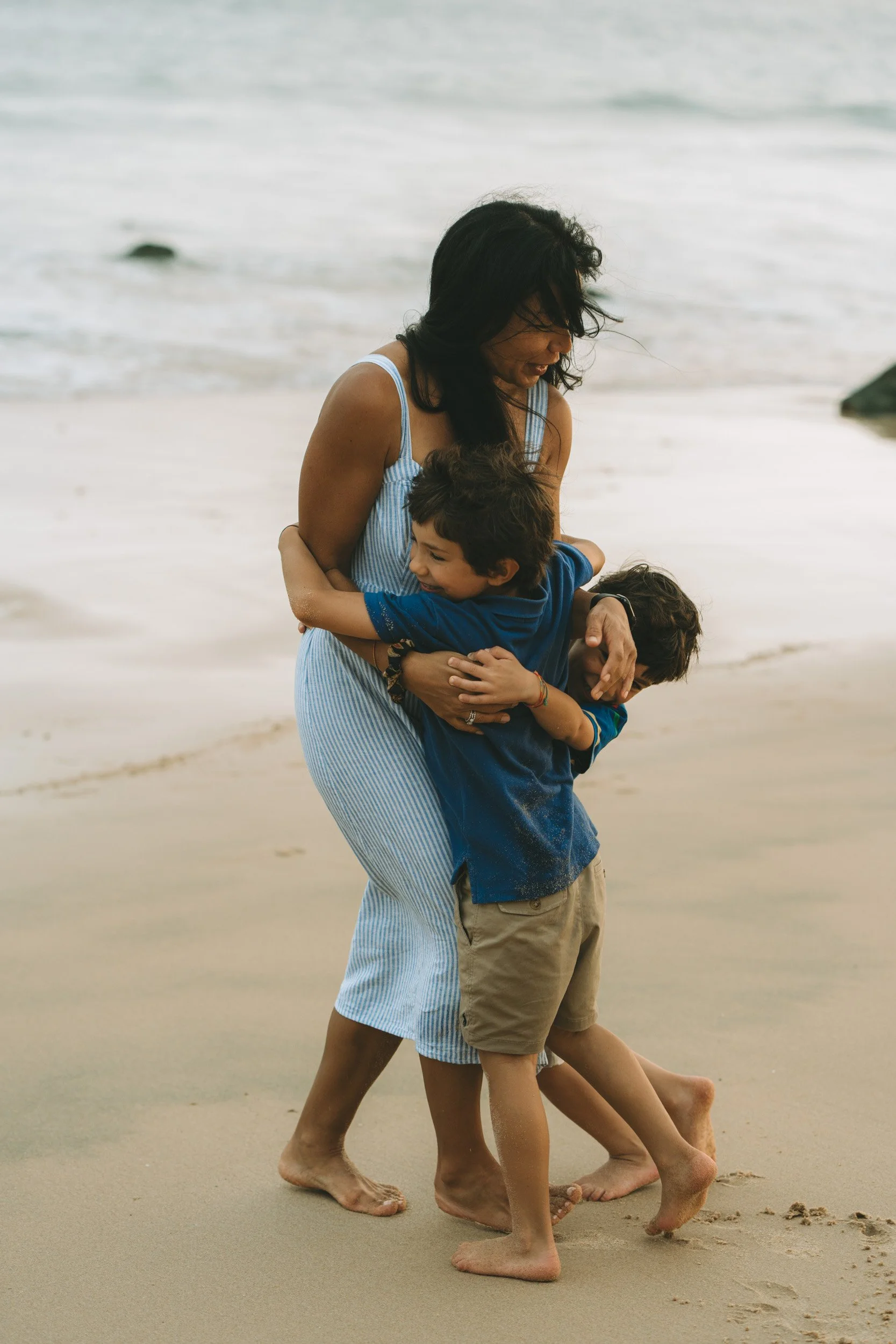 A quiet moment between mother and children near the water, photographed with a natural documentary approach.