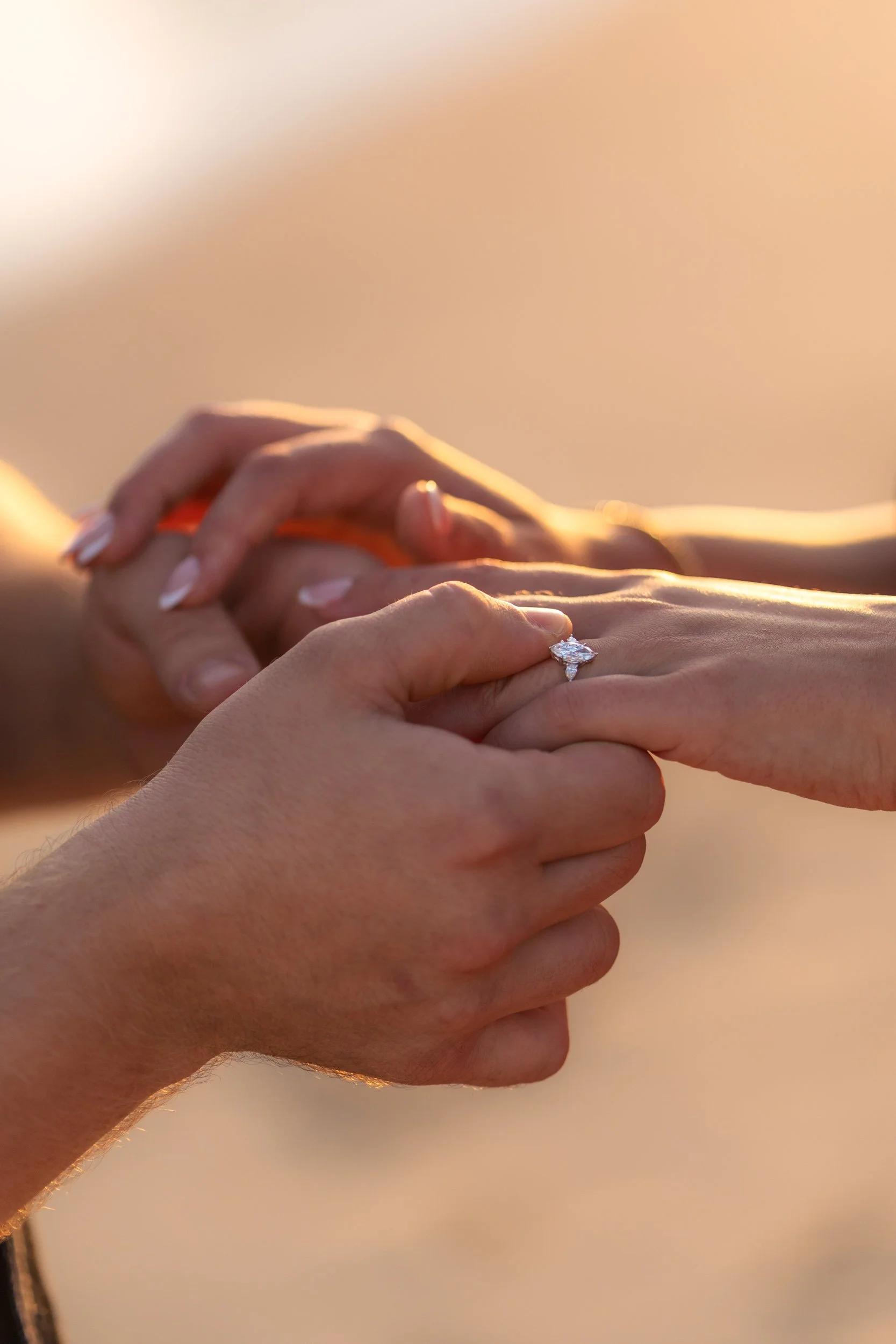 The exact moment the ring is placed on her finger — intimate, emotional and framed by warm sunset tones along the Algarve coast.