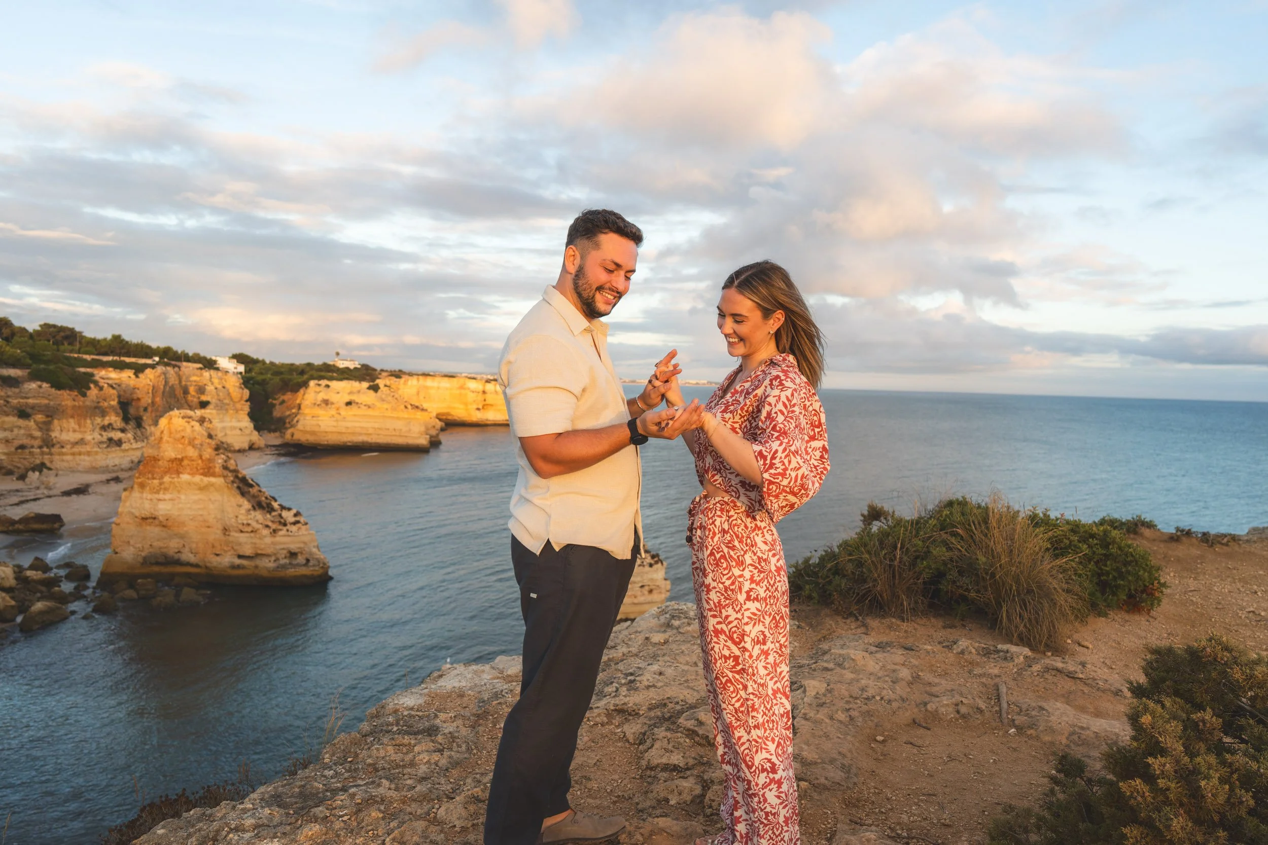 Proposal photoshoot in Praia da Marinha with panoramic cliff views, capturing the moment the engagement ring is placed.