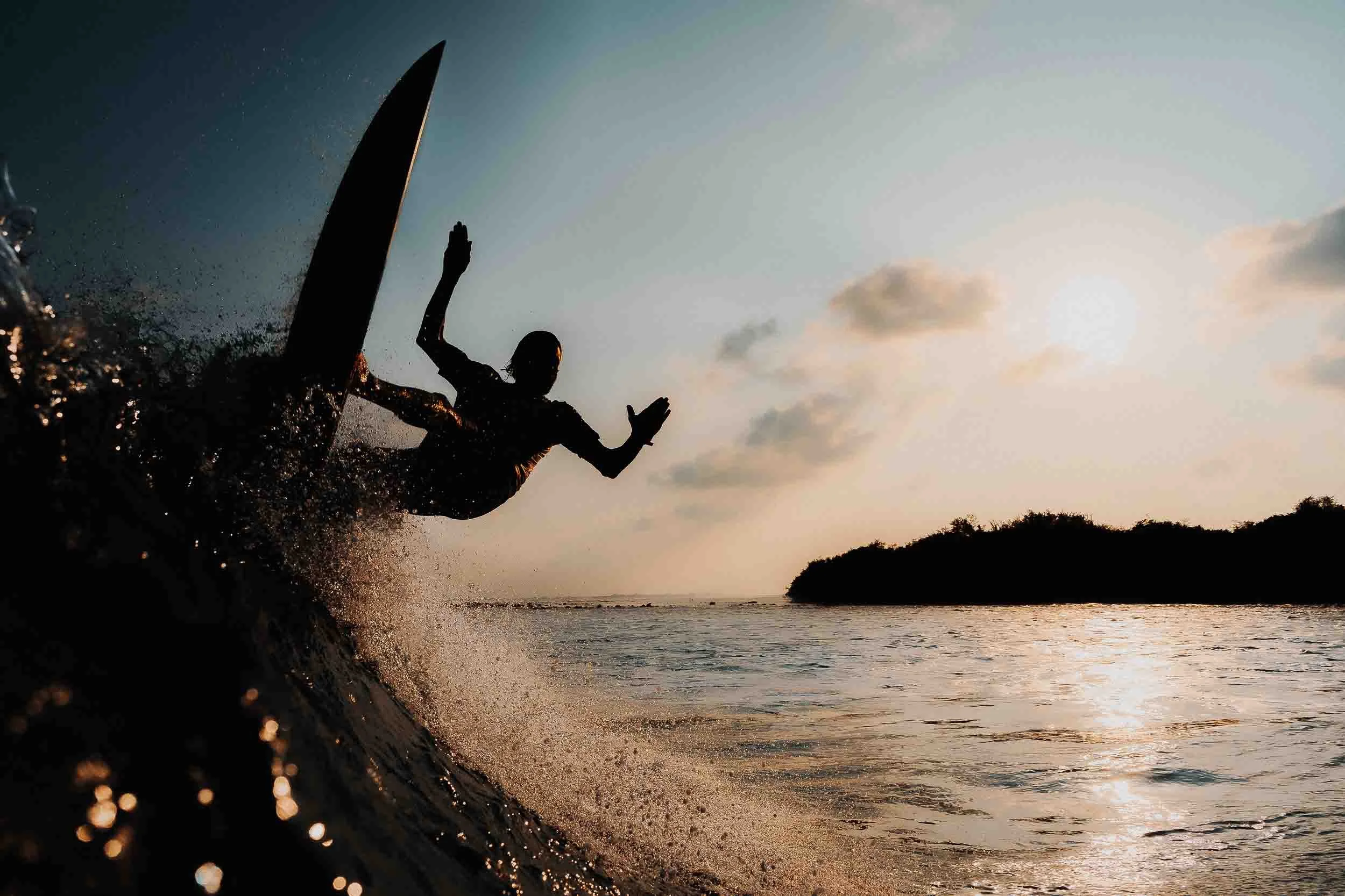 A silhouette of a person surfing on a wave during sunset or sunrise at the beach.